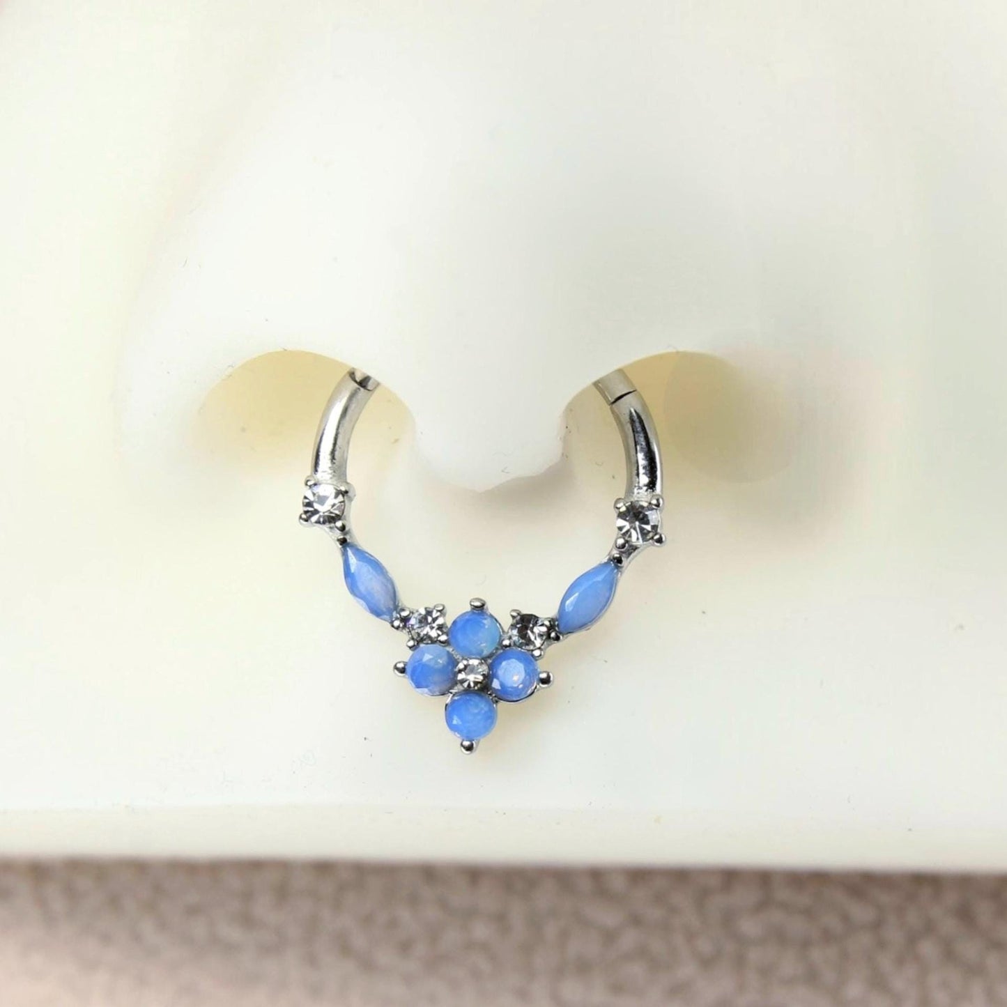MKBodyJewelry surgical steel septum clicker ring with blue opal floral gems and clear accents on a nose model