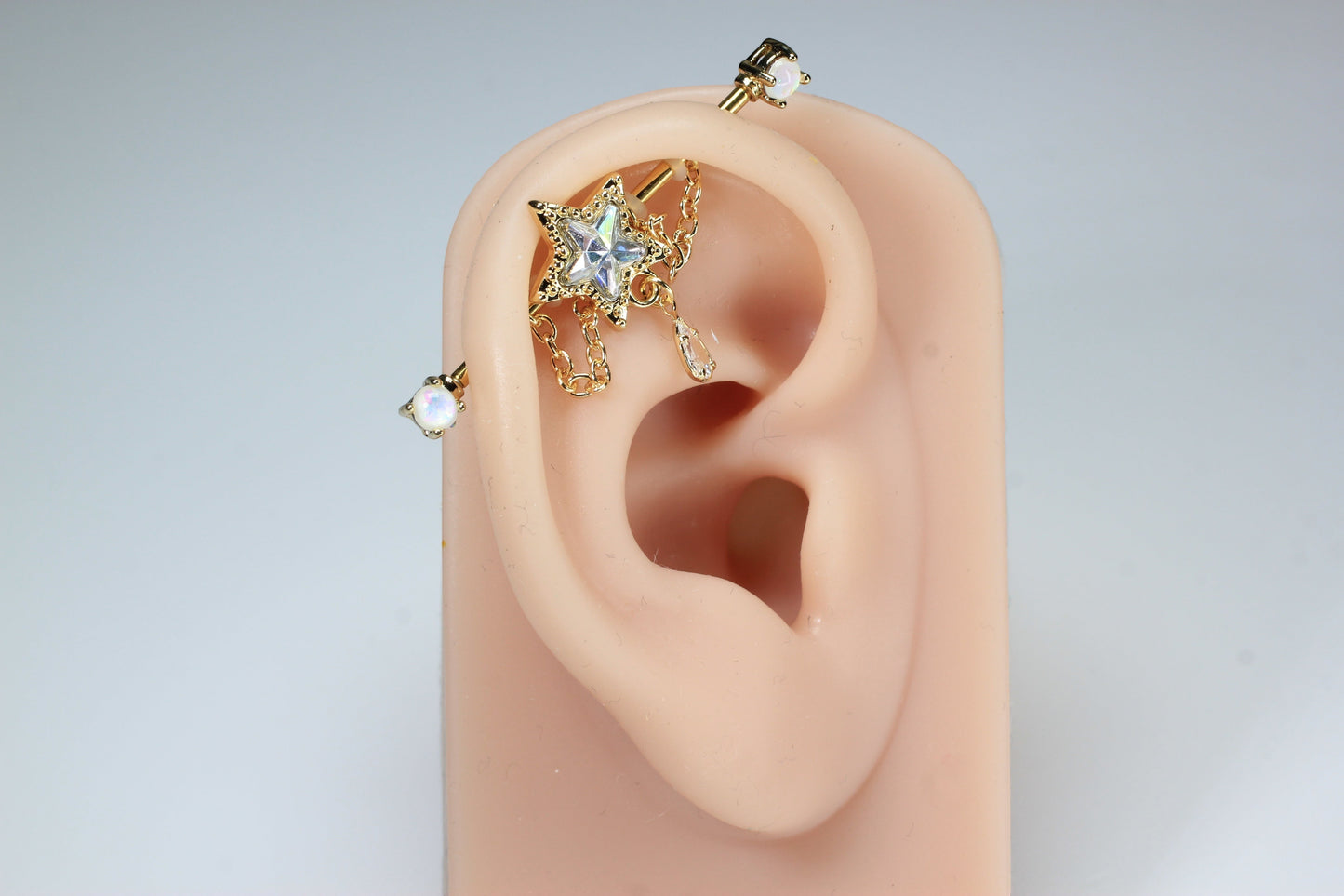 MKBodyJewelry 14G gold surgical steel industrial barbell with dangling star and chain, 35mm length, opal accents.