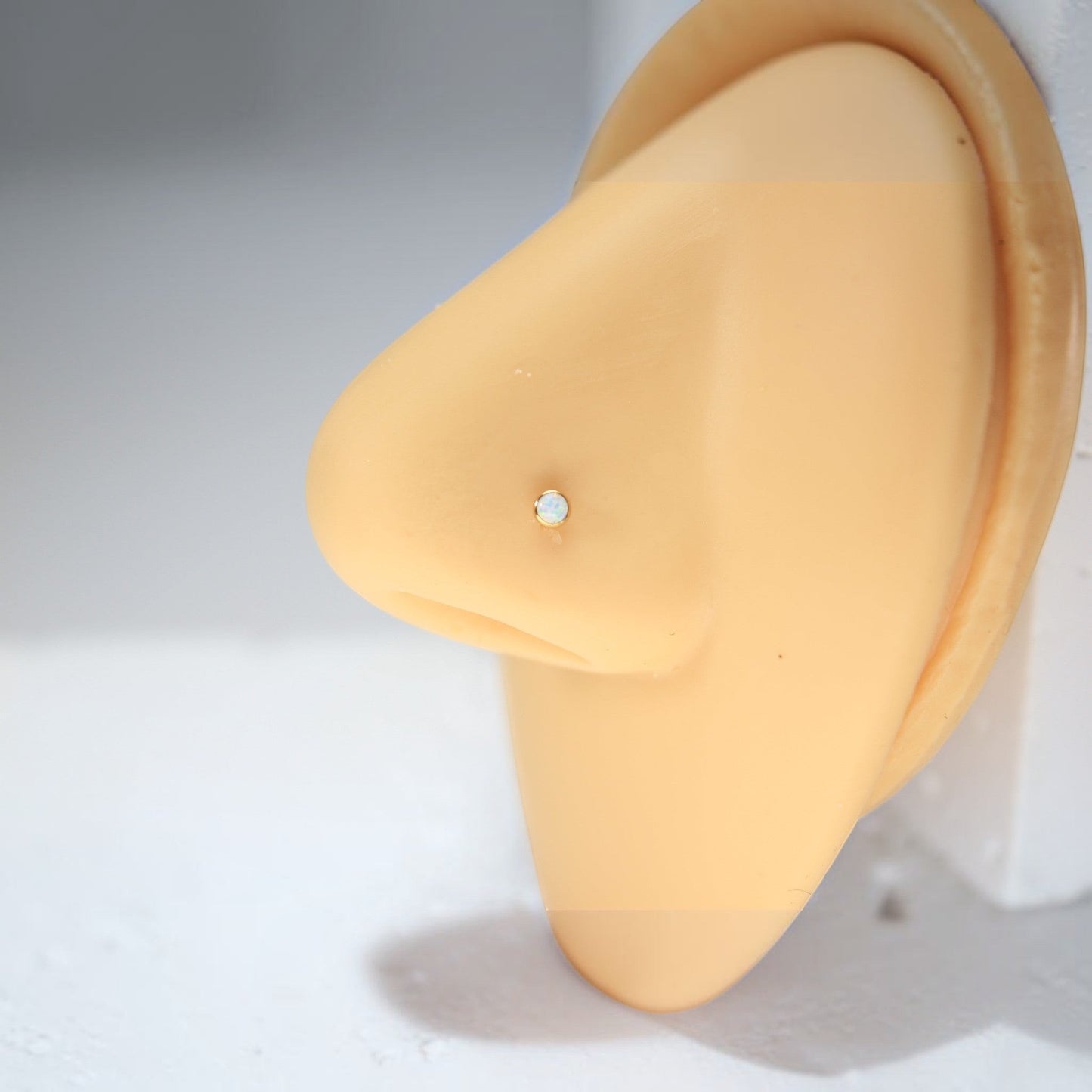 MKBodyJewelry 20G titanium nose stud with a 2.5mm opal gem on a mannequin nose for a minimalist piercing look.