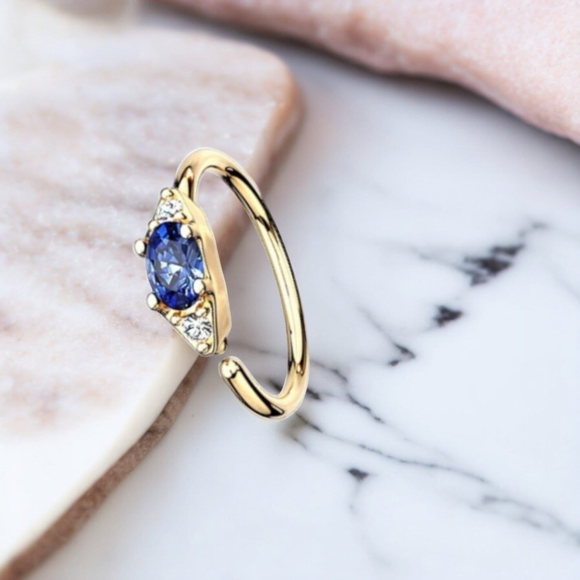 MKBodyJewelry 20g gold nose hoop with blue oval gem and clear accent gems. Bendable for nose or cartilage.