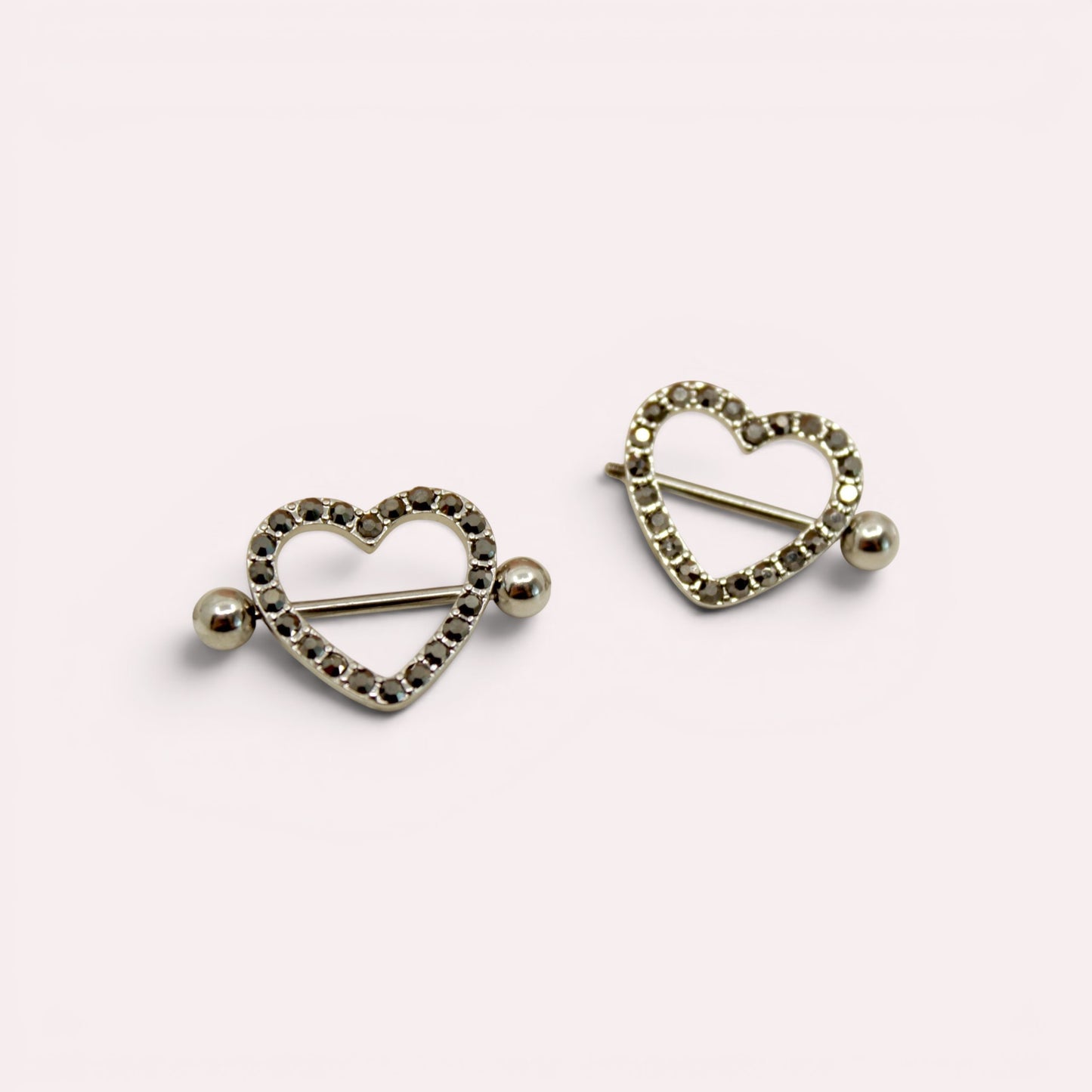 MKBodyJewelry pair of 14G surgical steel nipple barbells featuring silver heart shields with black paved gemstones.