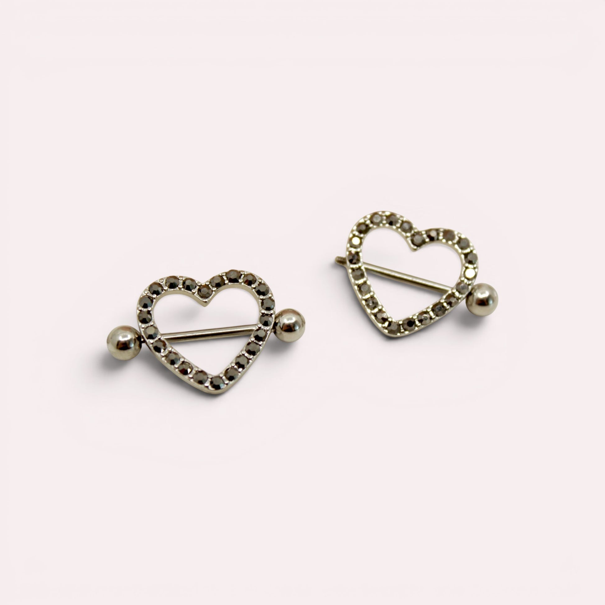 MKBodyJewelry pair of 14G surgical steel nipple barbells featuring silver heart shields with black paved gemstones.