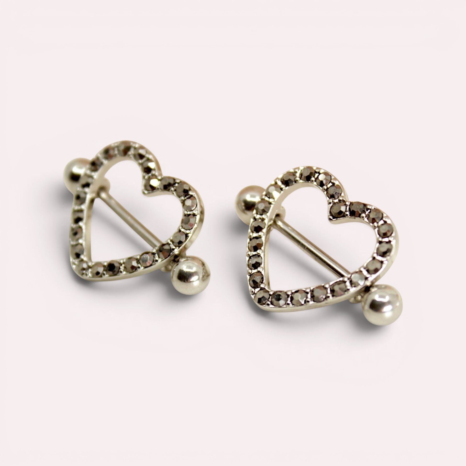 MKBodyJewelry pair of 14G surgical steel nipple barbells featuring silver heart shields with black paved gemstones.