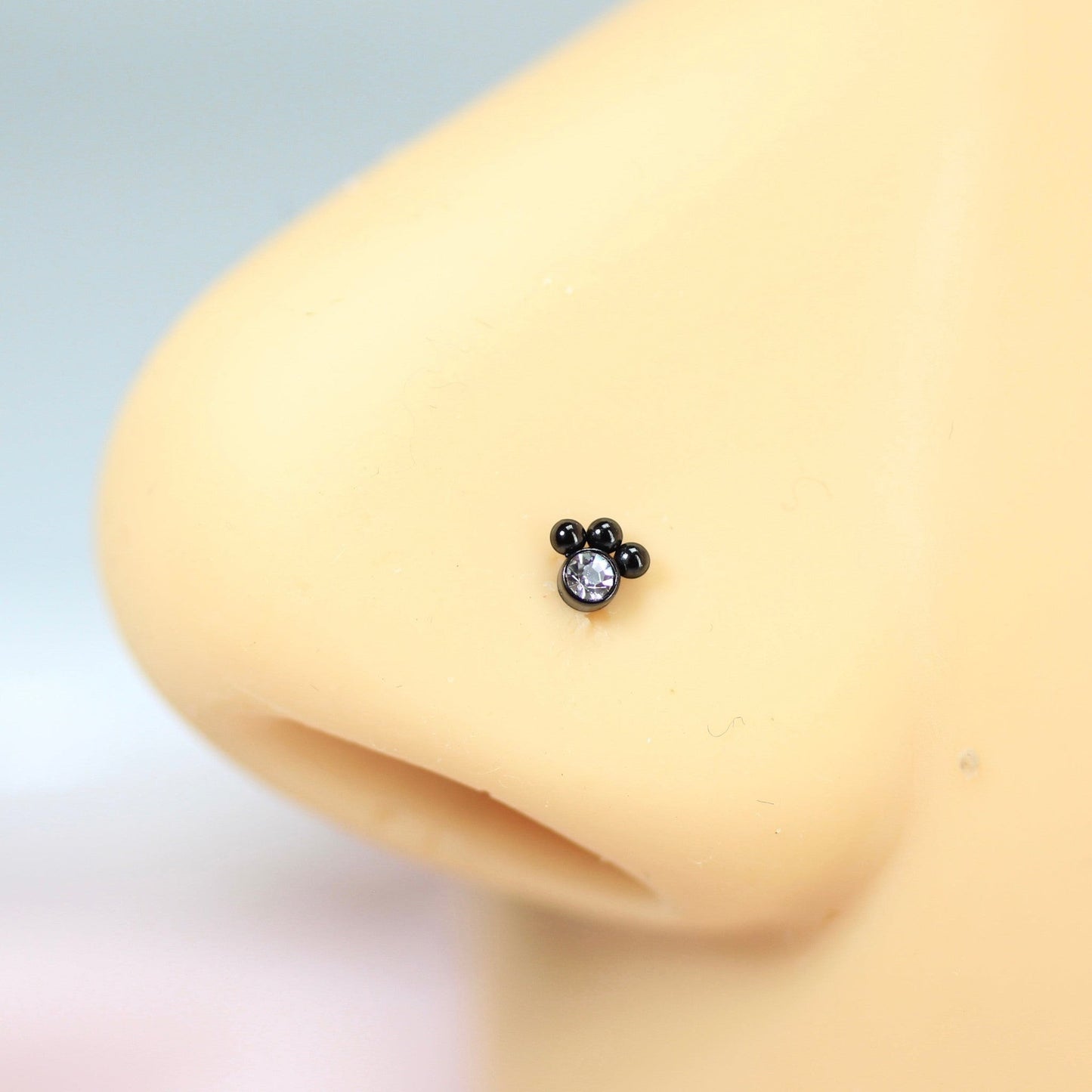 MKBodyJewelry black stainless steel paw print nose stud with a clear crystal accent on a nose model
