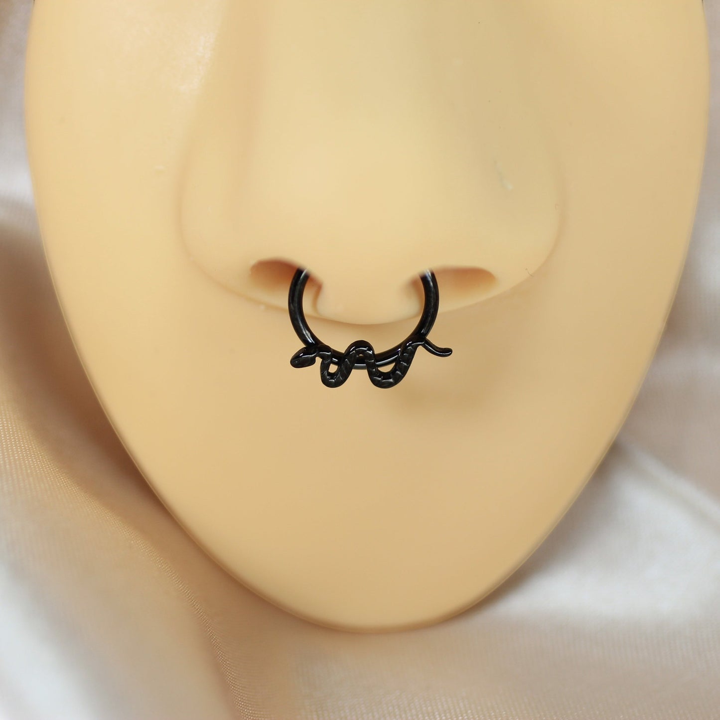 MKBodyJewelry 16g black titanium snake septum clicker ring with a minimalist hinged hoop design on a nose mannequin.