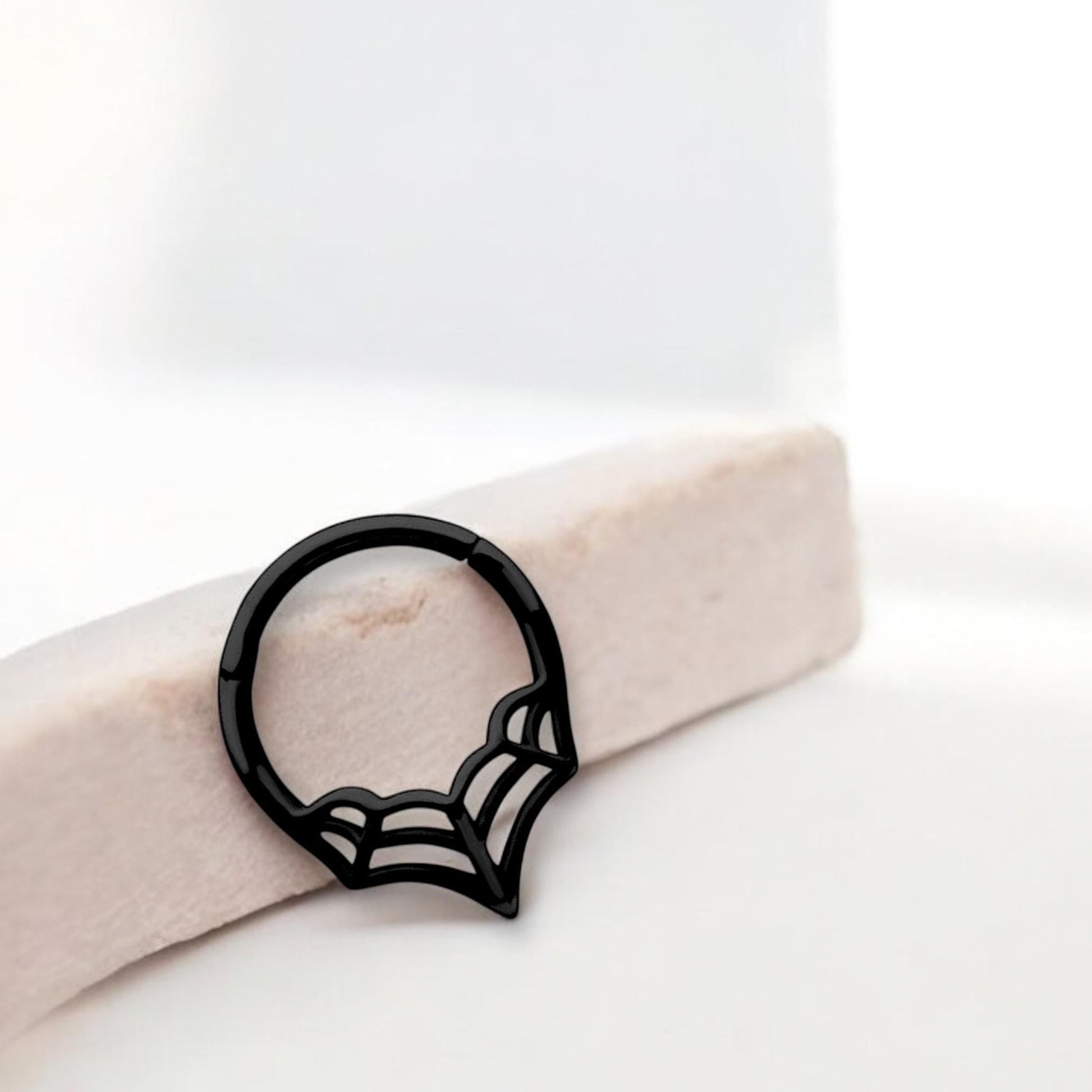 MKBodyJewelry 16G black surgical steel spider web septum clicker ring with a hinged segment design.