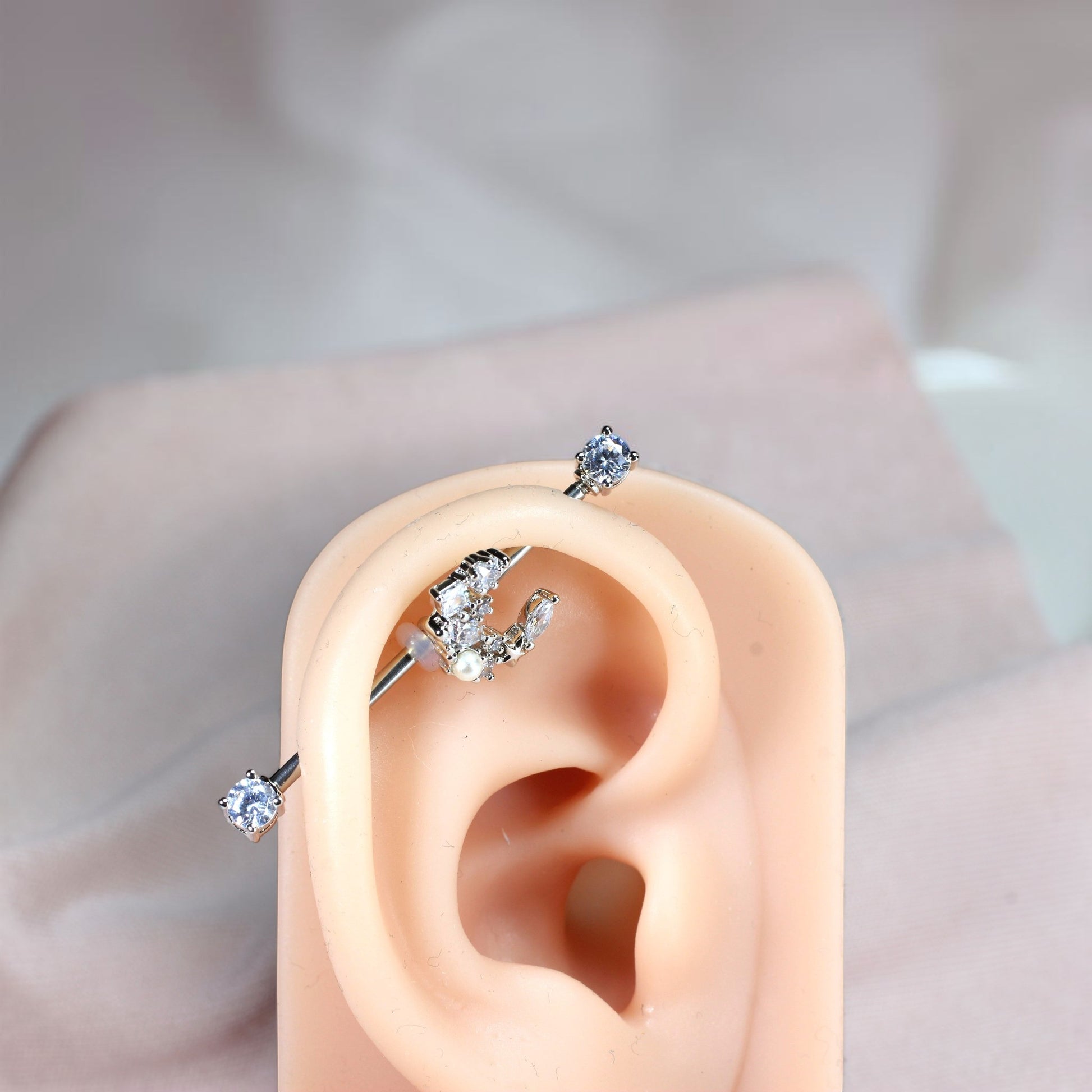 MKBodyJewelry 14G surgical steel industrial barbell with a dainty crescent moon charm adorned with cubic zirconia and a pearl.