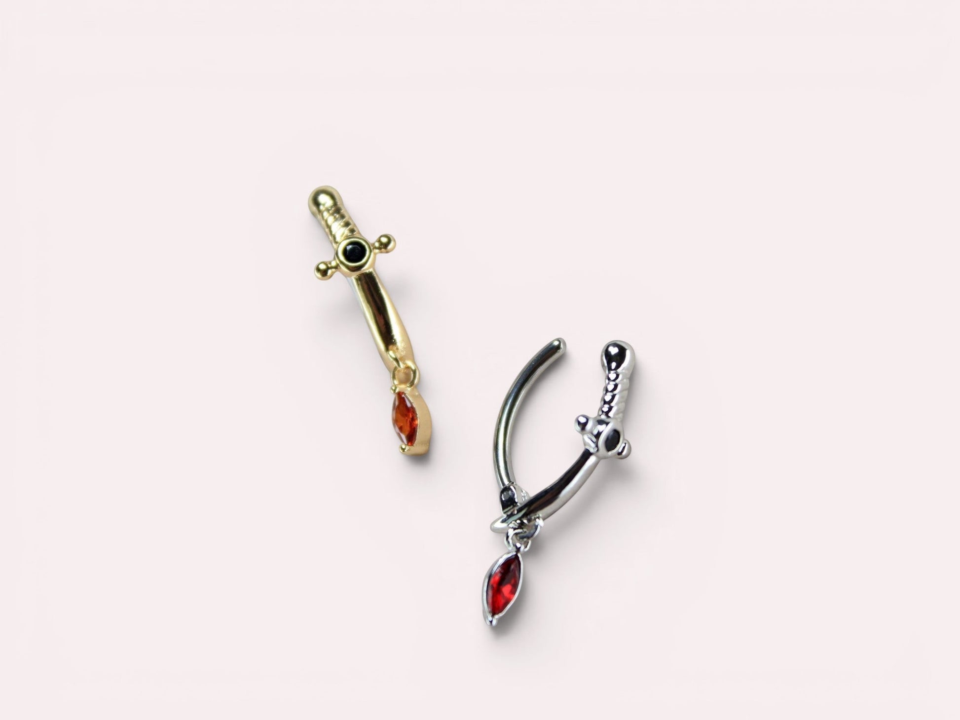 MKBodyJewelry gold and silver dagger belly button rings with red CZ gems and black accents. 14G stainless steel.