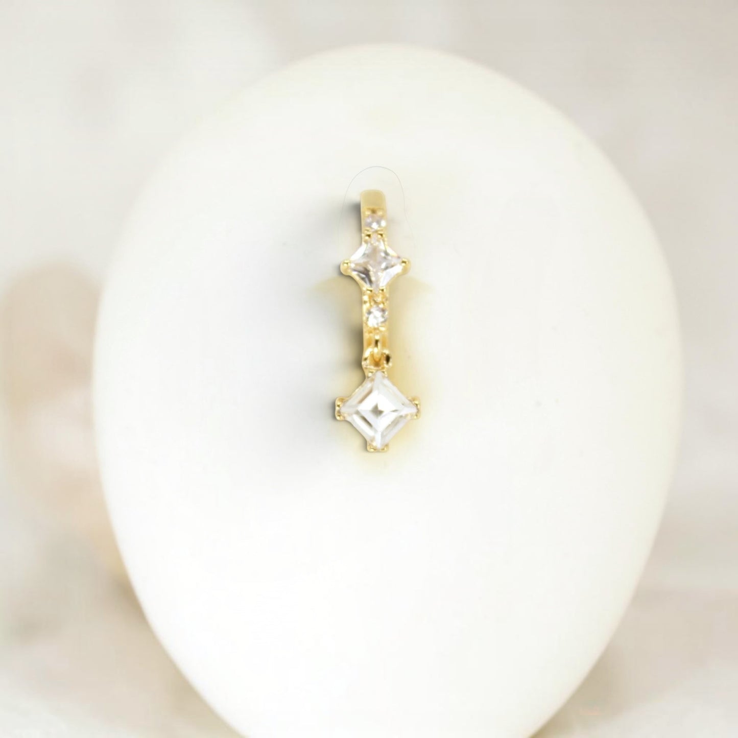 MKBodyJewelry gold-tone dangling belly button ring with clear cubic zirconia stones in square settings.