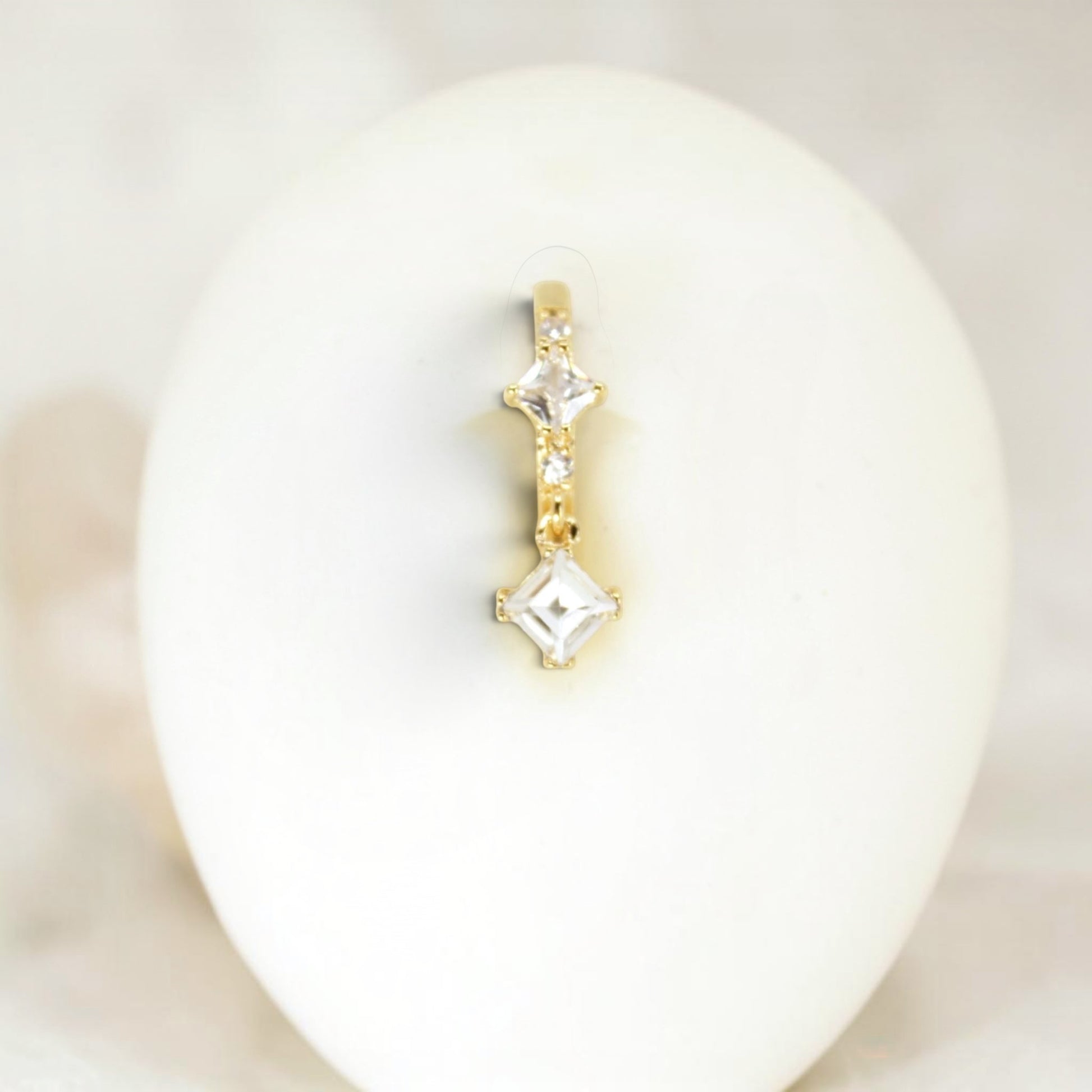MKBodyJewelry gold-tone dangling belly button ring with clear cubic zirconia stones in square settings.