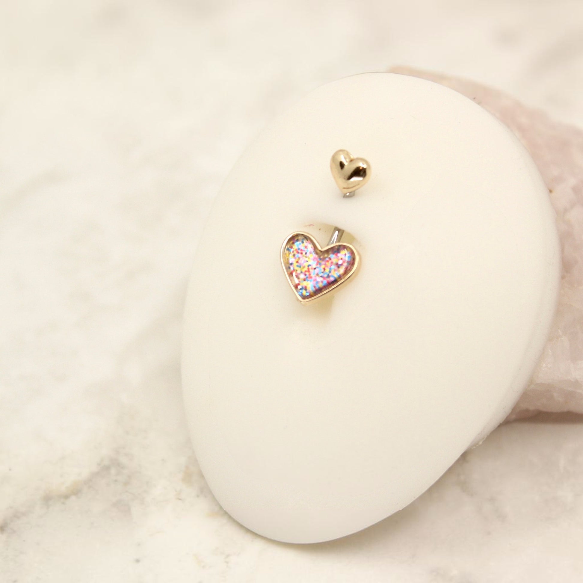 MKBodyJewelry 14G surgical steel belly button ring featuring a gold-tone heart charm with colorful glitter resin.