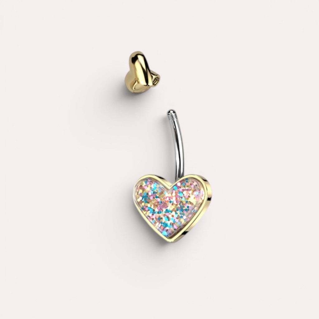 MKBodyJewelry 14G surgical steel belly button ring featuring a gold heart charm filled with colorful glitter.