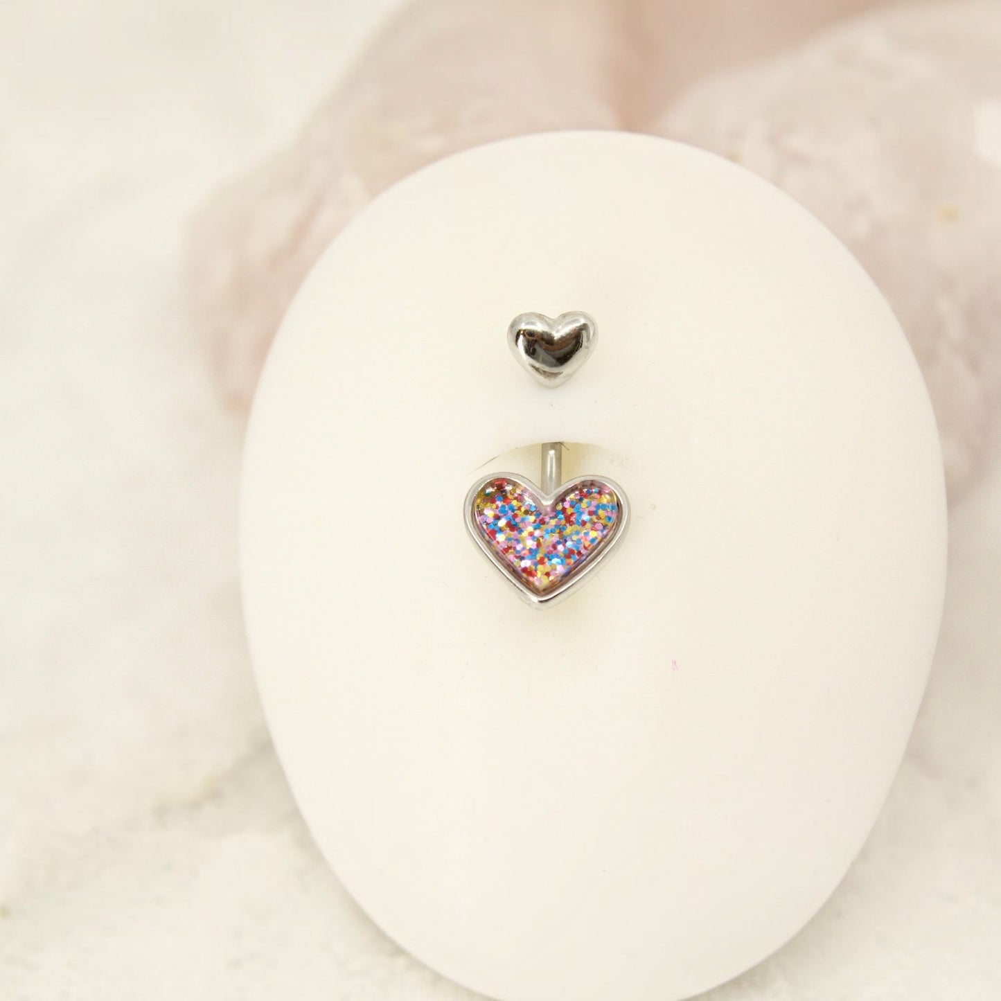 MKBodyJewelry 14G surgical steel belly button ring featuring a cute resin heart charm filled with colorful glitter.