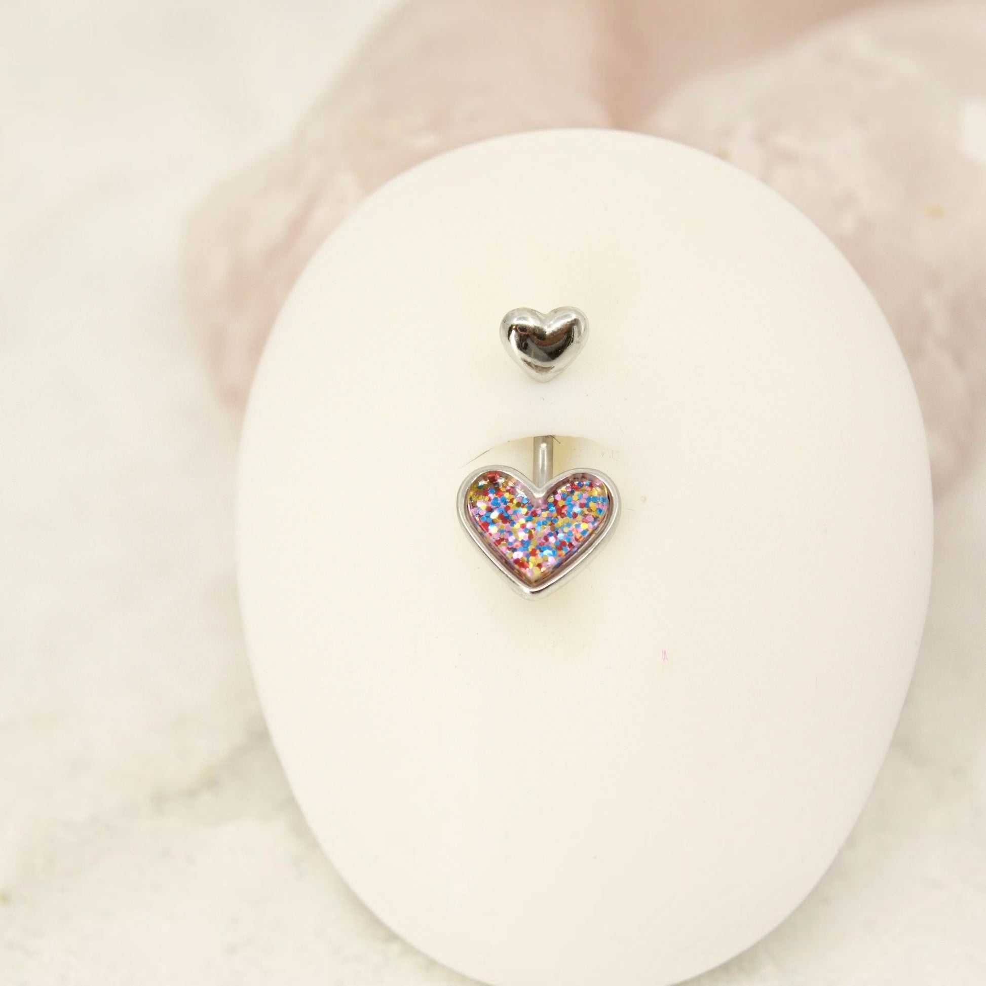 MKBodyJewelry 14G surgical steel belly button ring featuring a cute resin heart charm filled with colorful glitter.