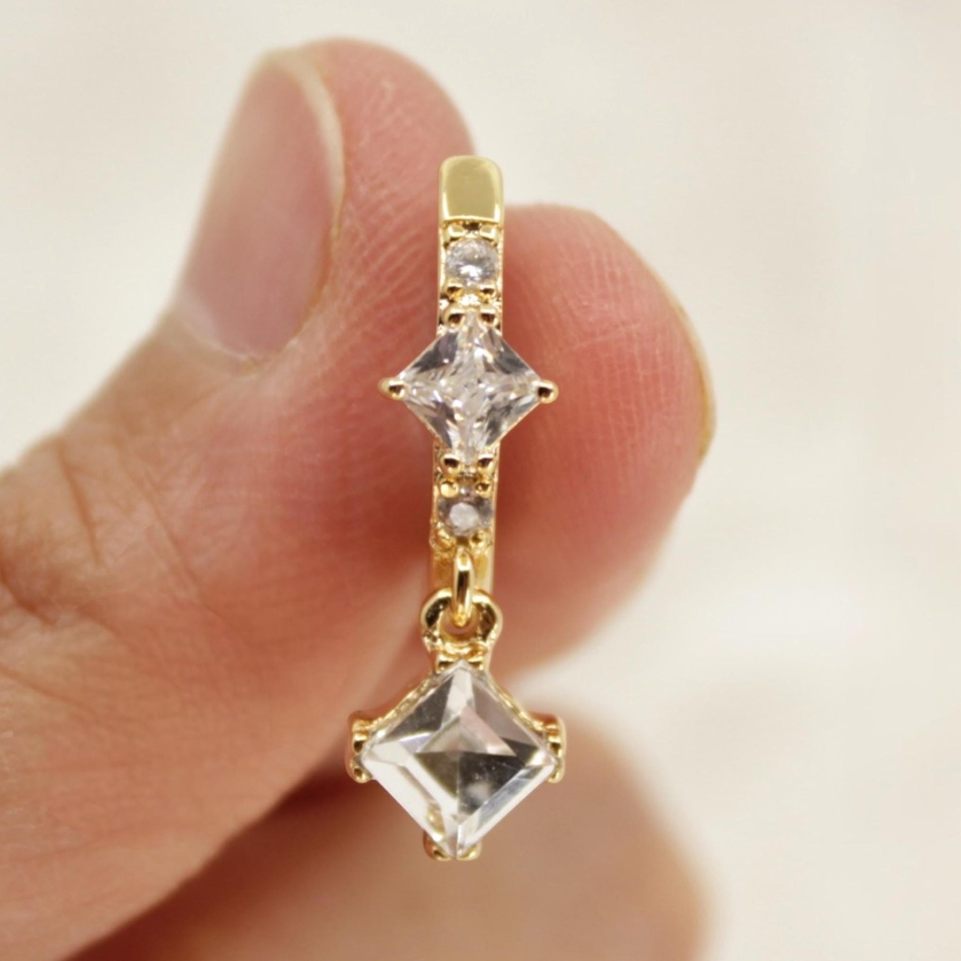 MKBodyJewelry gold-tone stainless steel dangling belly button ring with clear cubic zirconia stones in square settings.