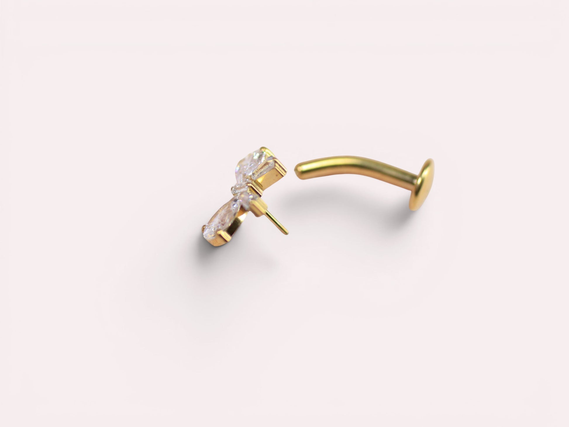 MKBodyJewelry dainty gold titanium threadless bow belly ring with clear cubic zirconia stones.