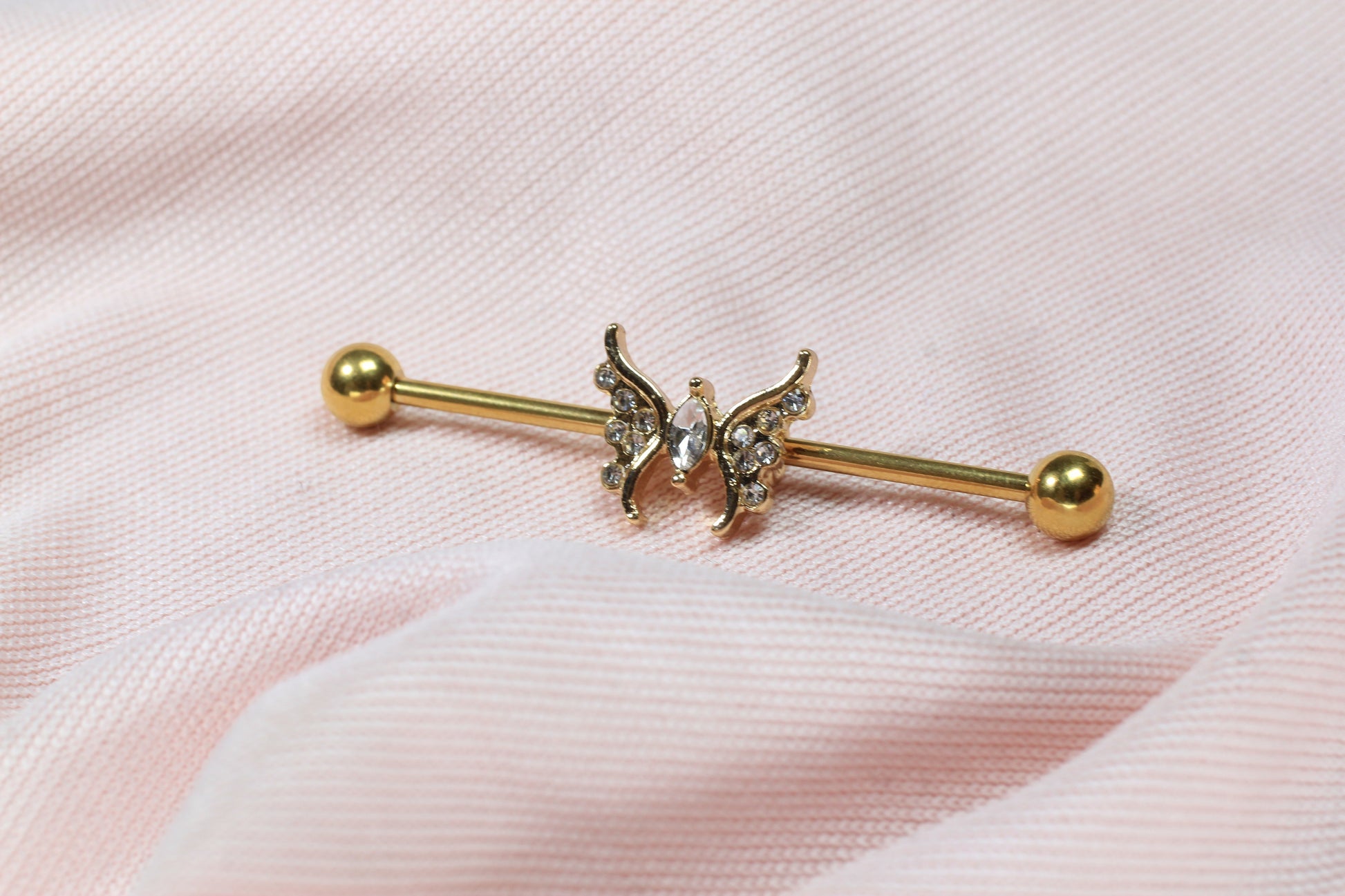 14G gold industrial barbell with a dainty CZ butterfly charm.