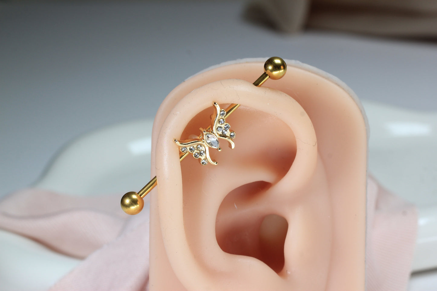 MKBodyJewelry gold 14G surgical steel industrial barbell with a dainty CZ butterfly charm, 35mm length.