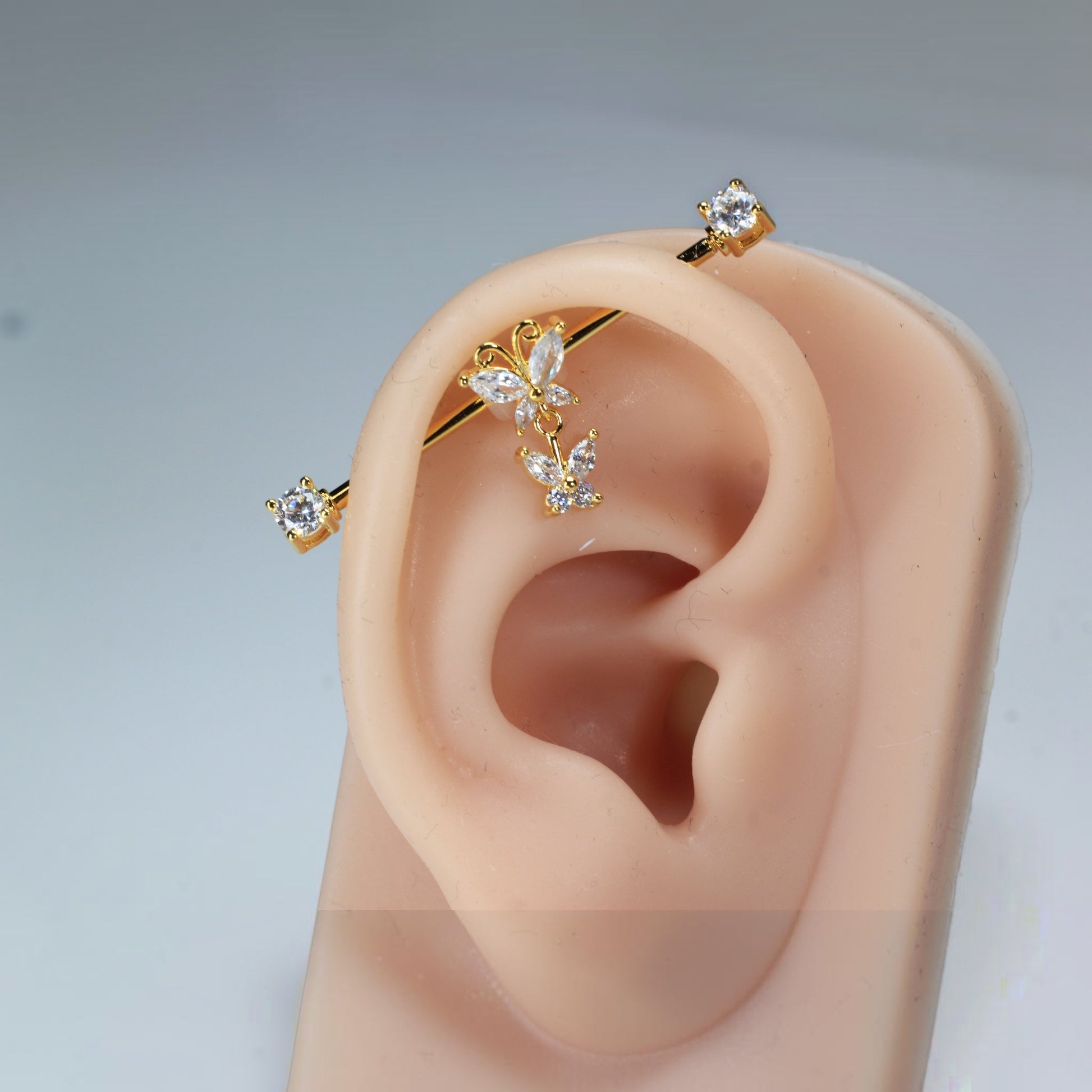 MKBodyJewelry gold surgical steel industrial barbell with dangling butterfly charms and clear cubic zirconia.