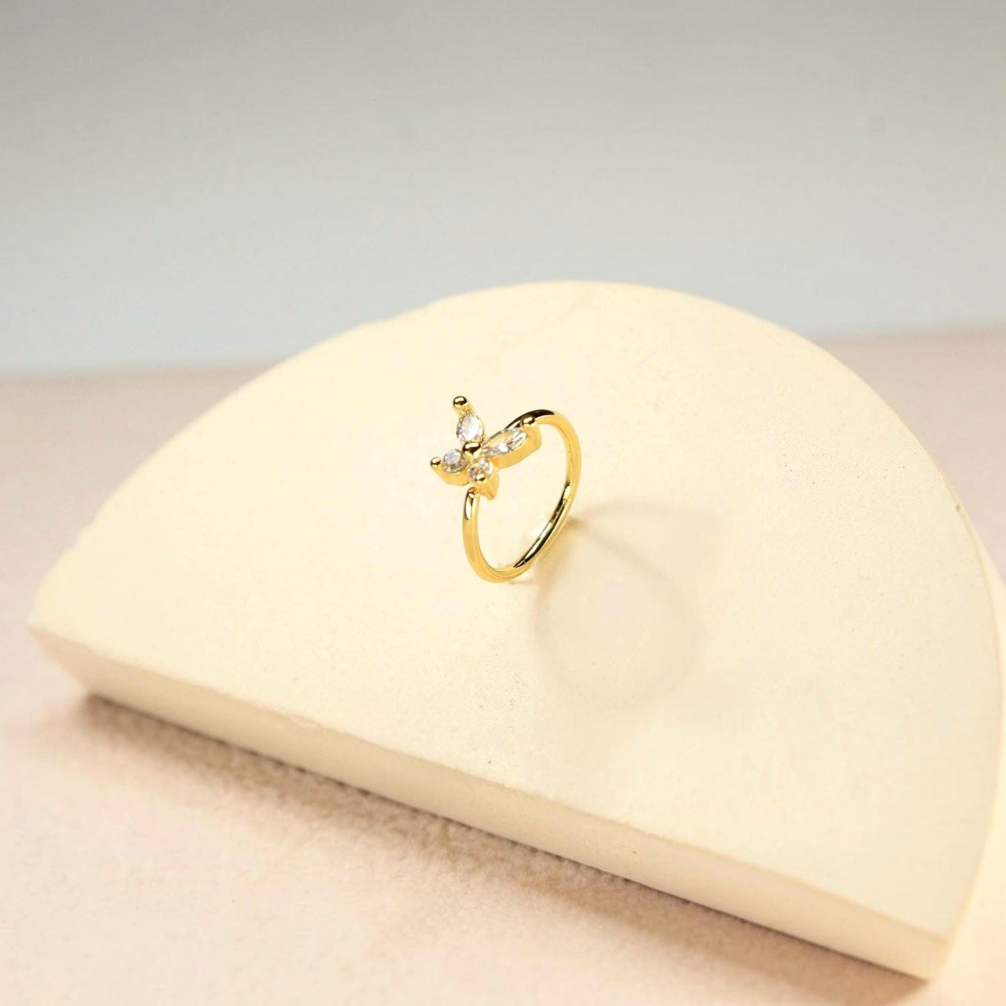 MKBodyJewelry gold 20g surgical steel nose hoop featuring a dainty CZ butterfly charm on a minimalist bendable ring.