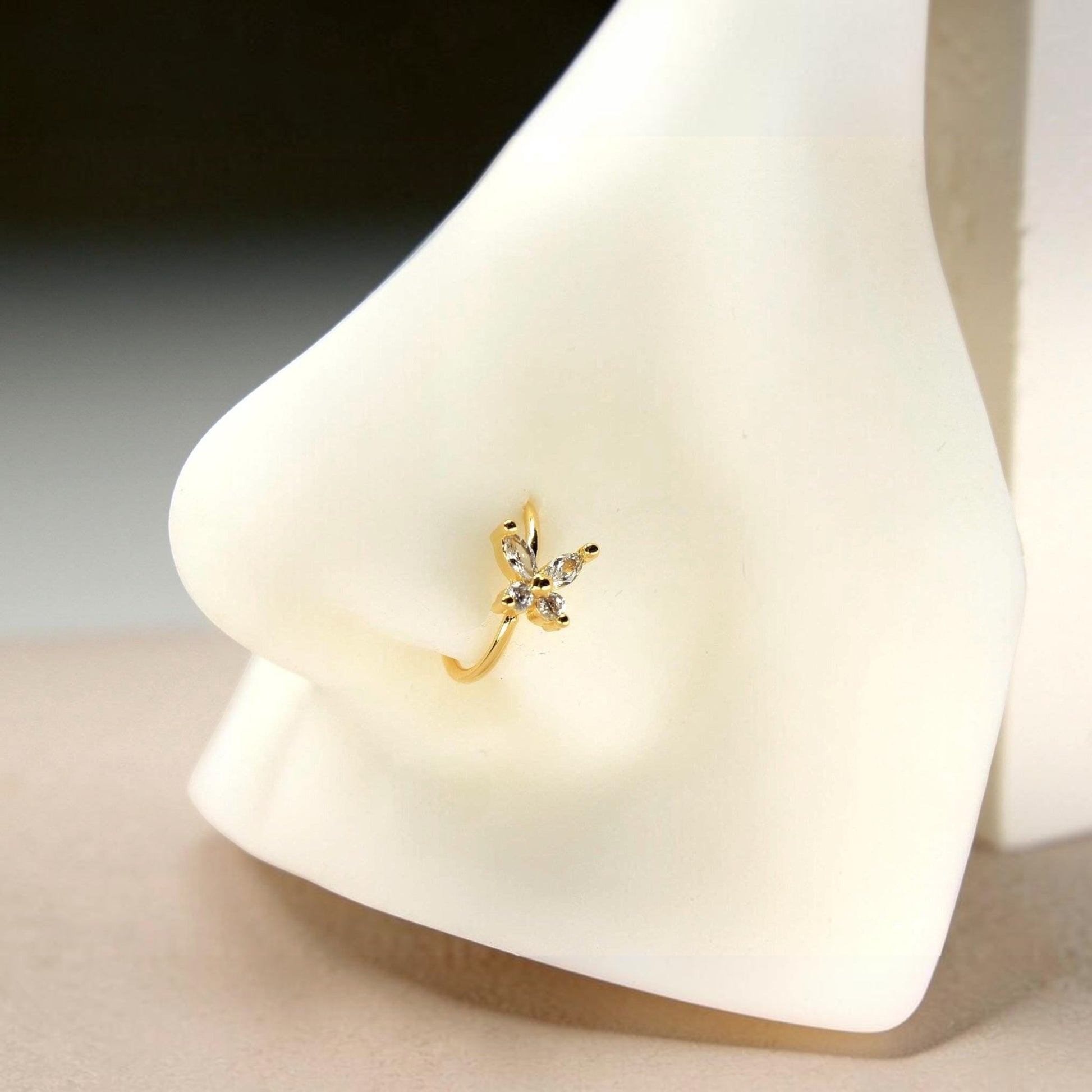 MKBodyJewelry gold surgical steel nose hoop featuring a dainty butterfly charm with clear CZ stones on a nose model.