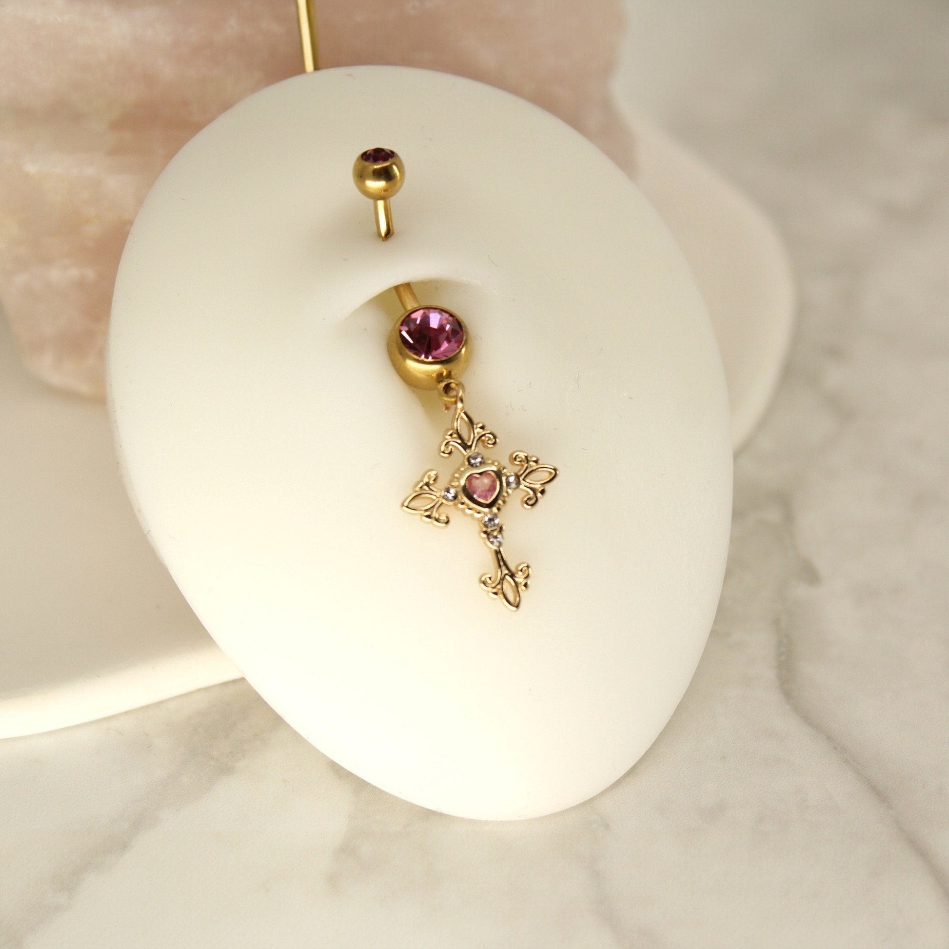 MKBodyJewelry gold tone surgical steel belly ring with a hot pink gem and a dangling ornate cross charm