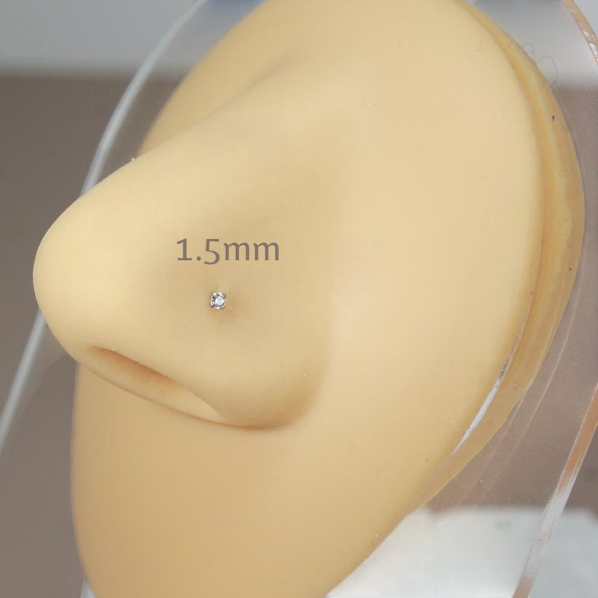 MKBodyJewelry 1.5mm gold-tone nose stud with a round-cut cubic zirconia in a four-prong setting on a mannequin nose.