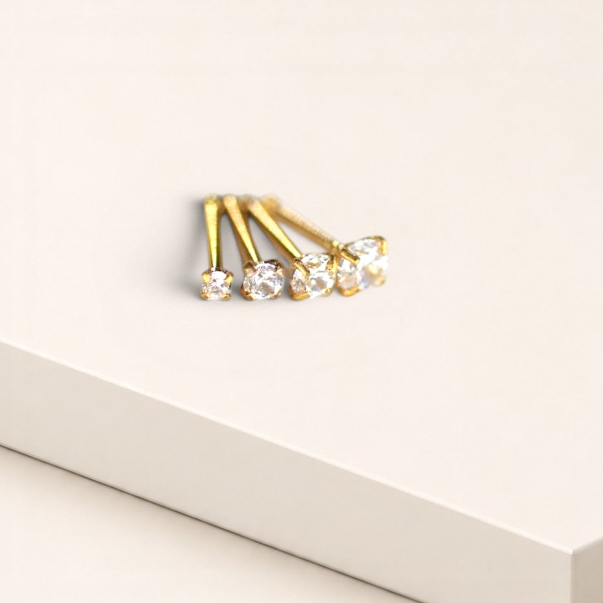 MKBodyJewelry gold-tone nose studs with round-cut cubic zirconia stones in four-prong settings on a white background.
