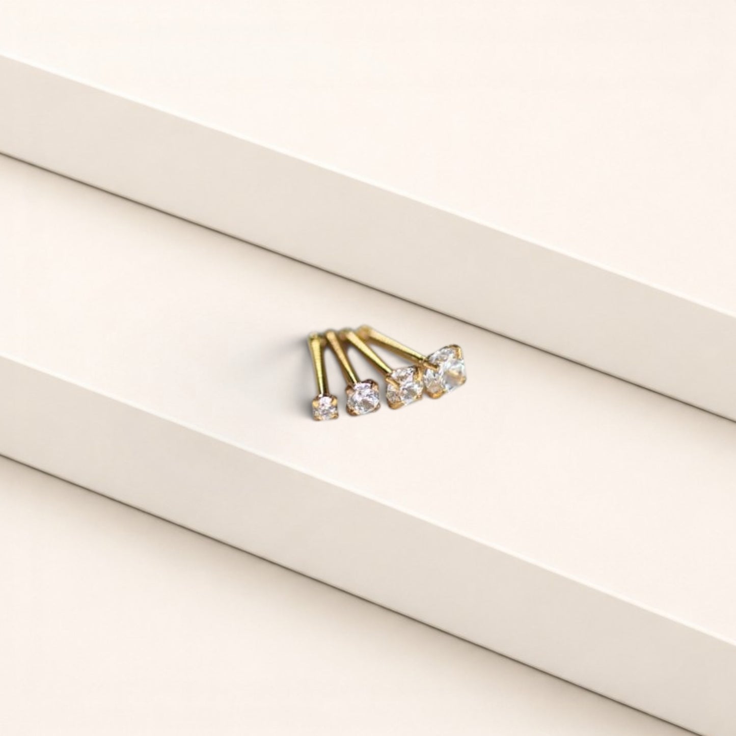 MKBodyJewelry gold-tone nose studs with round-cut cubic zirconia stones in a classic four-prong setting.