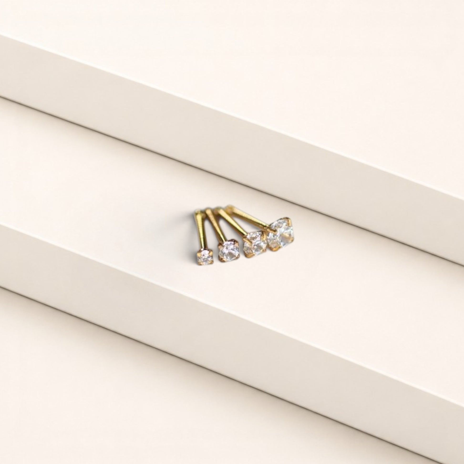 MKBodyJewelry gold-tone nose studs with round-cut cubic zirconia stones in a classic four-prong setting.