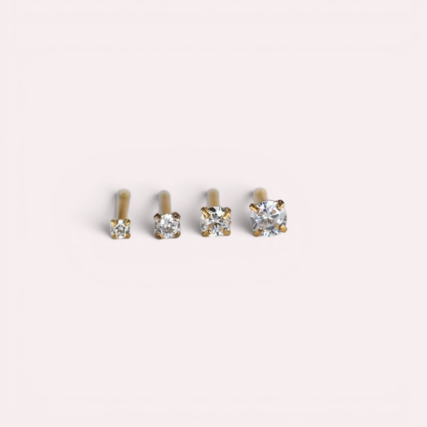 MKBodyJewelry gold-tone nose studs with round-cut cubic zirconia stones in four-prong settings of varying sizes.