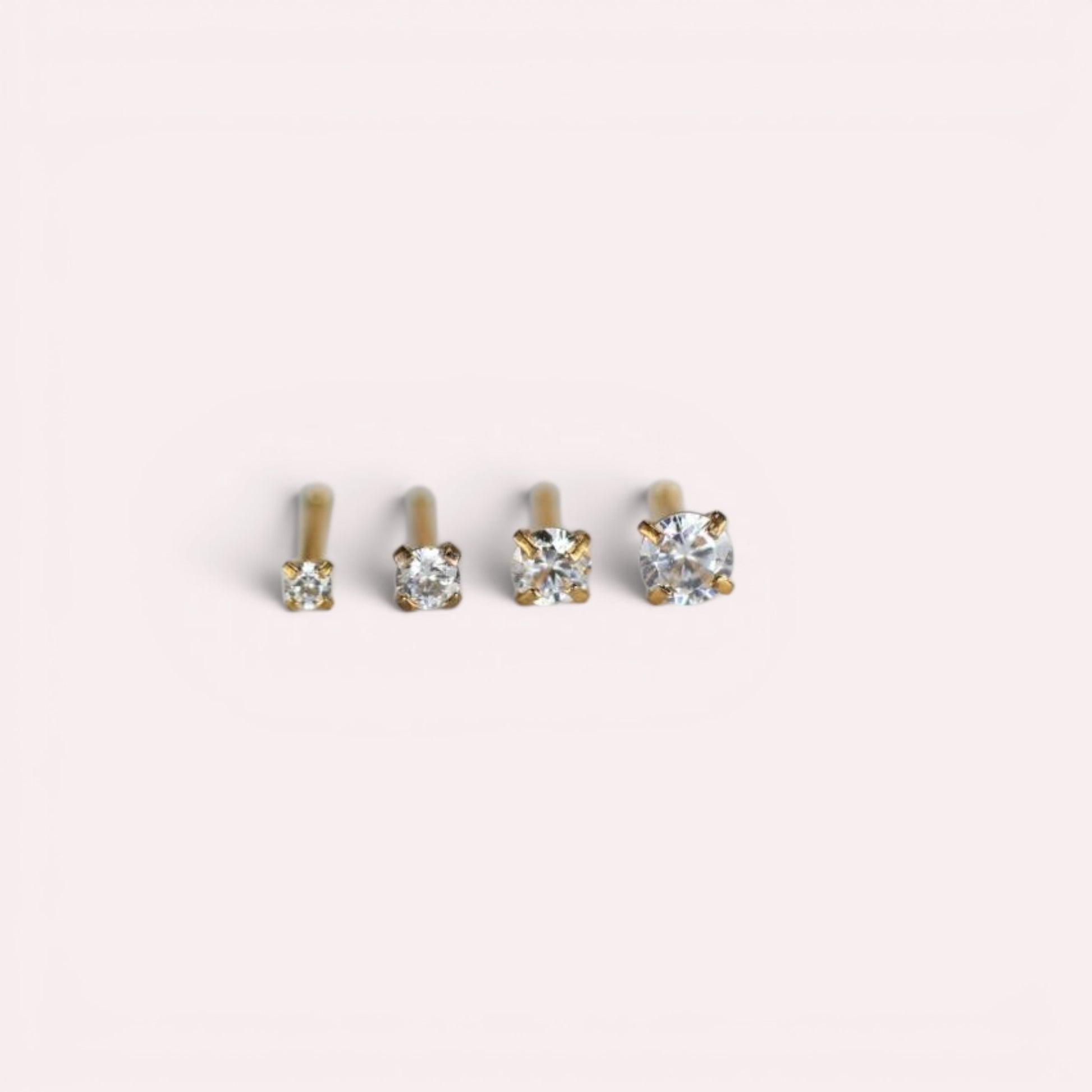 MKBodyJewelry gold-tone nose studs with round-cut cubic zirconia stones in four-prong settings of varying sizes.