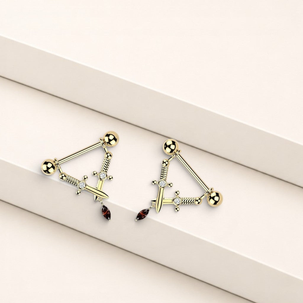 MKBodyJewelry 14g gold dagger nipple barbell pair with sword design, clear crystals, and a dangling red gemstone.