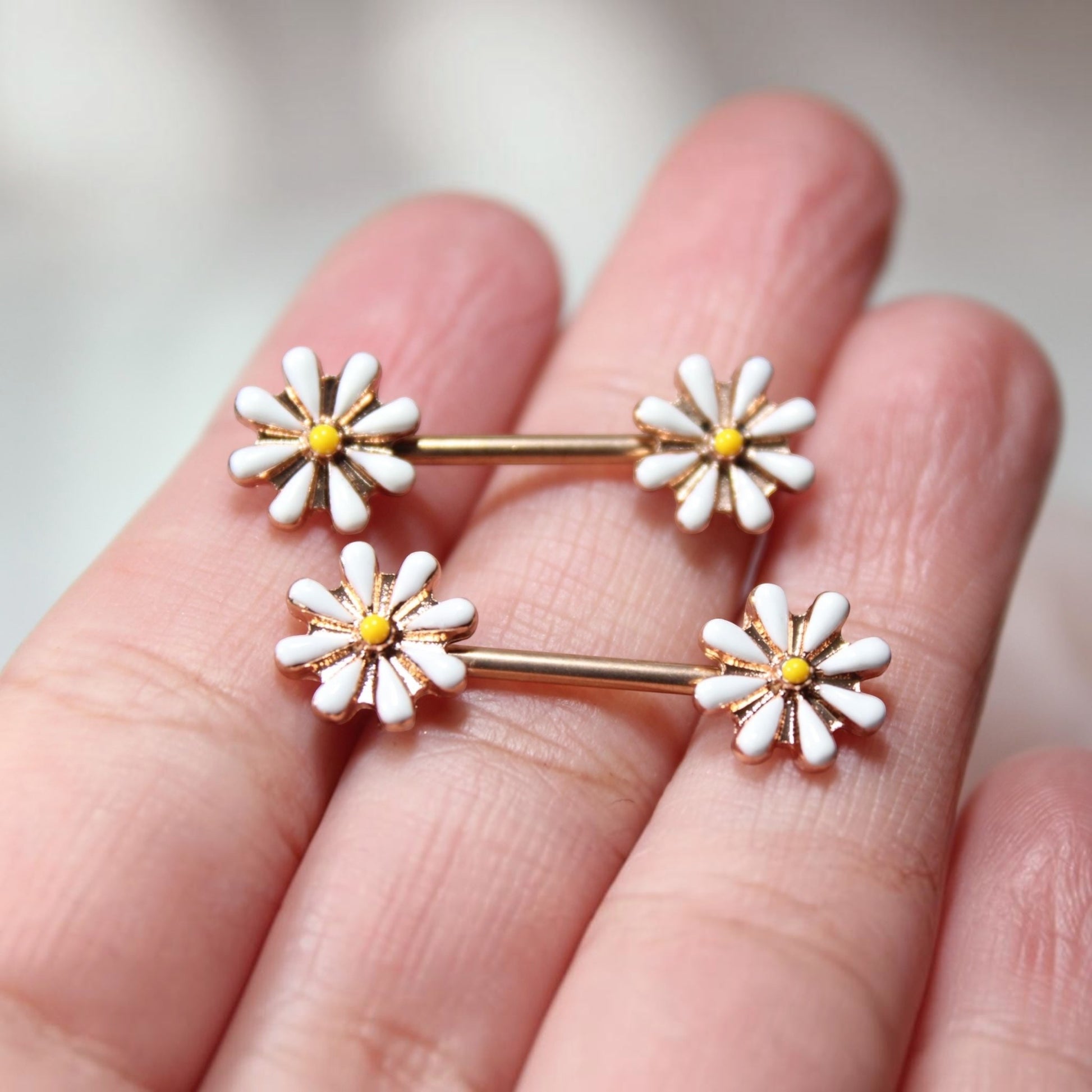 MKBodyJewelry 14G gold surgical steel nipple barbells featuring white and yellow daisy flower designs, sold as a pair.
