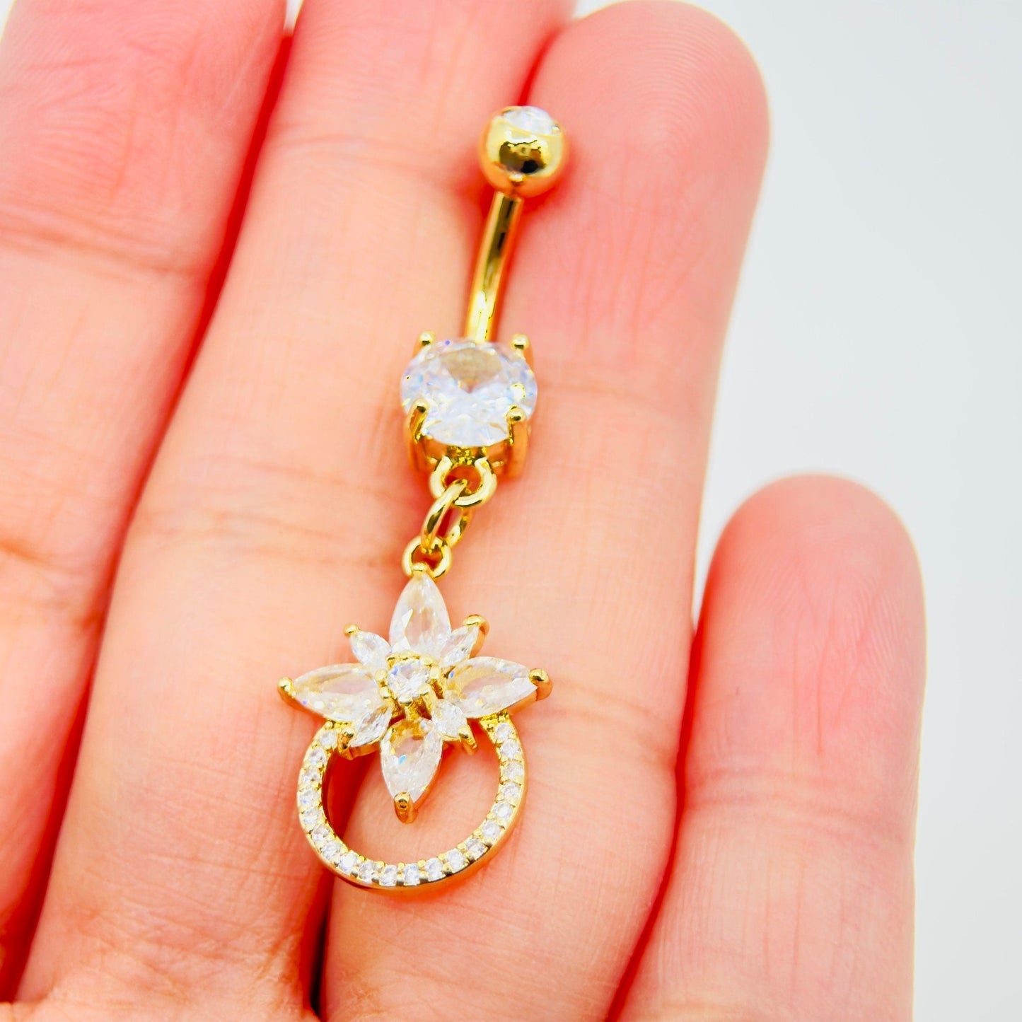 MKBodyJewelry 14g gold surgical steel belly button ring featuring a dangling floral charm with sparkling CZ stones.