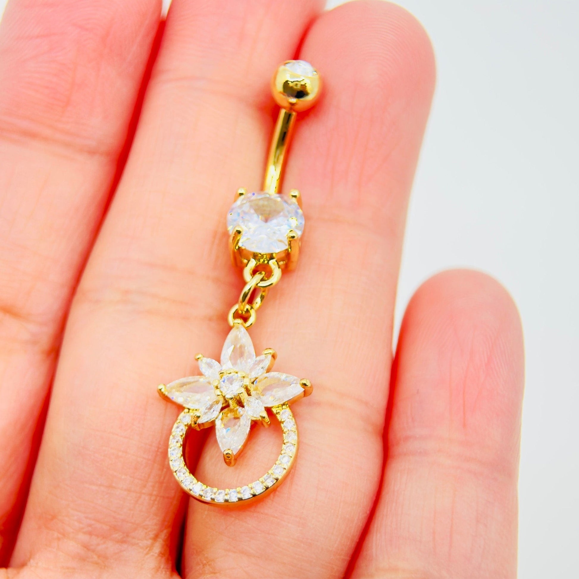MKBodyJewelry 14g gold surgical steel belly button ring featuring a dangling floral charm with sparkling CZ stones.