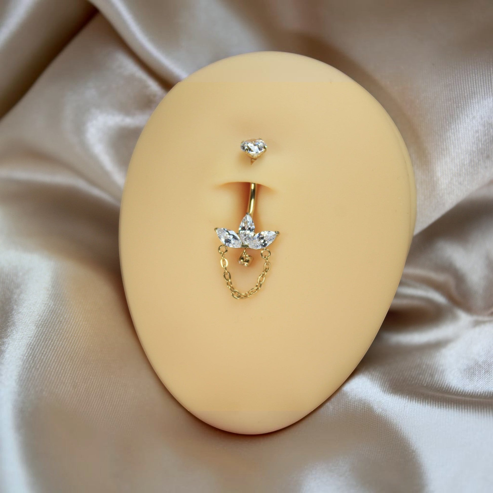 MKBodyJewelry 14g gold titanium belly ring with a floral marquise gem dangle chain on a navel piercing display model.