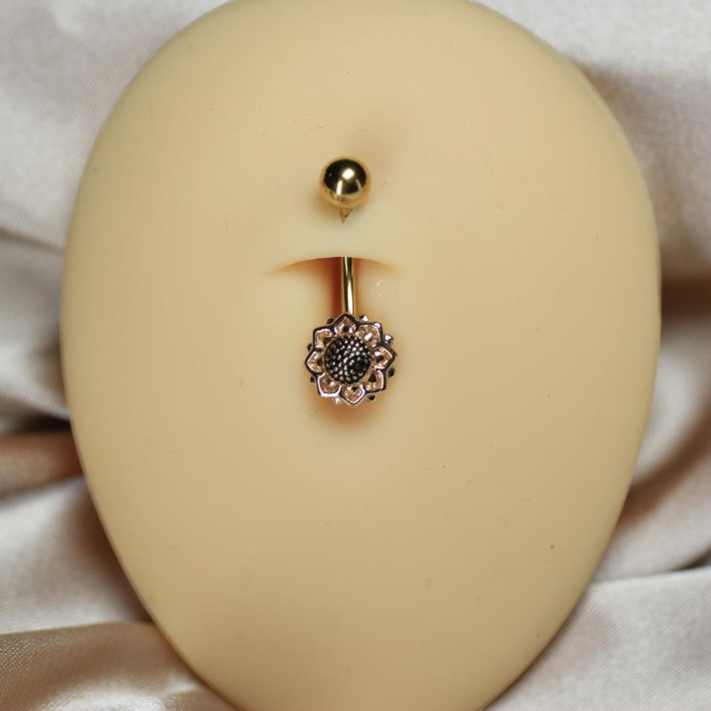MKBodyJewelry 14G gold floral belly button ring made of hypoallergenic surgical steel on a mannequin torso