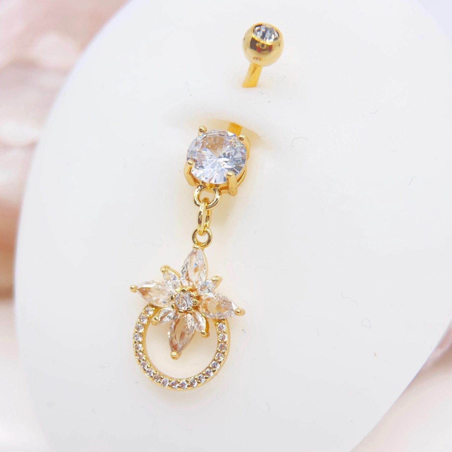MKBodyJewelry 14g gold surgical steel belly button ring with a dangling floral charm and sparkling CZ stones.
