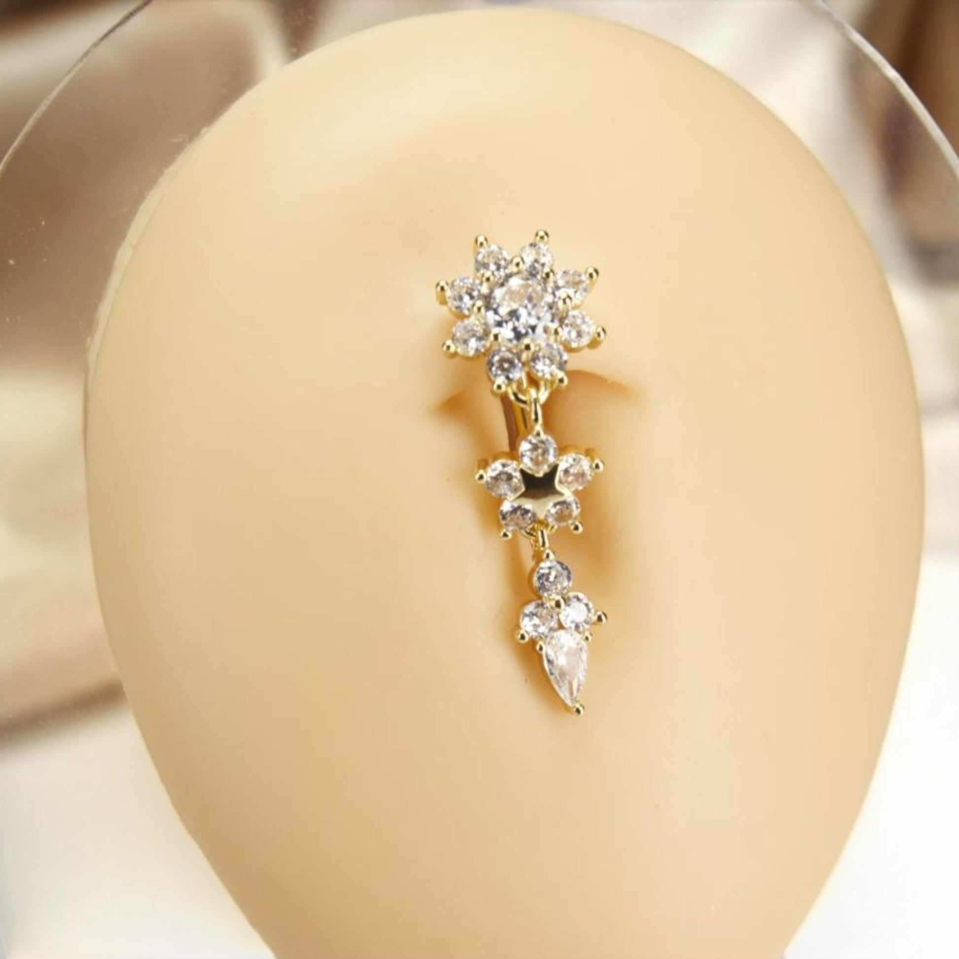 MKBodyJewelry gold-tone dangling belly button ring with floral, star, and teardrop cubic zirconia charms.