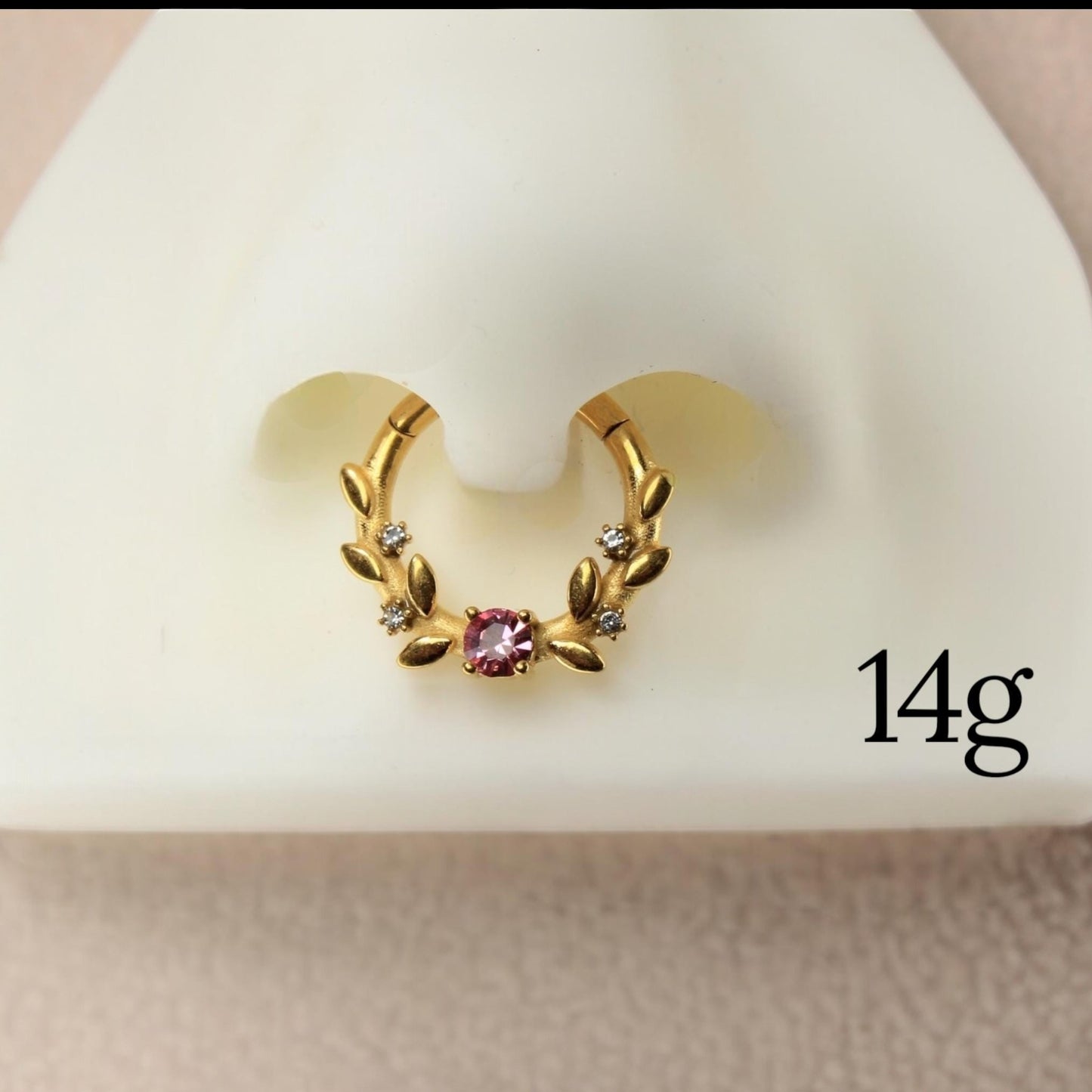 MKBodyJewelry gold floral septum clicker ring with a pink center gem and clear accent stones on a display nose.