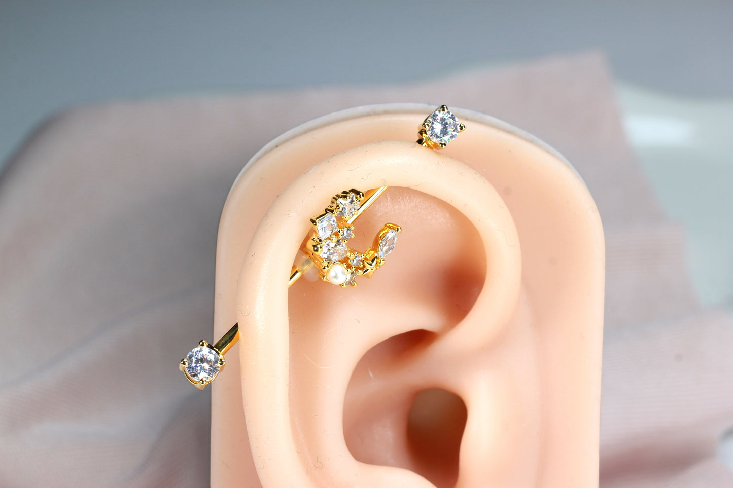 MKBodyJewelry gold industrial barbell with a crescent moon charm adorned with cubic zirconia and pearls.