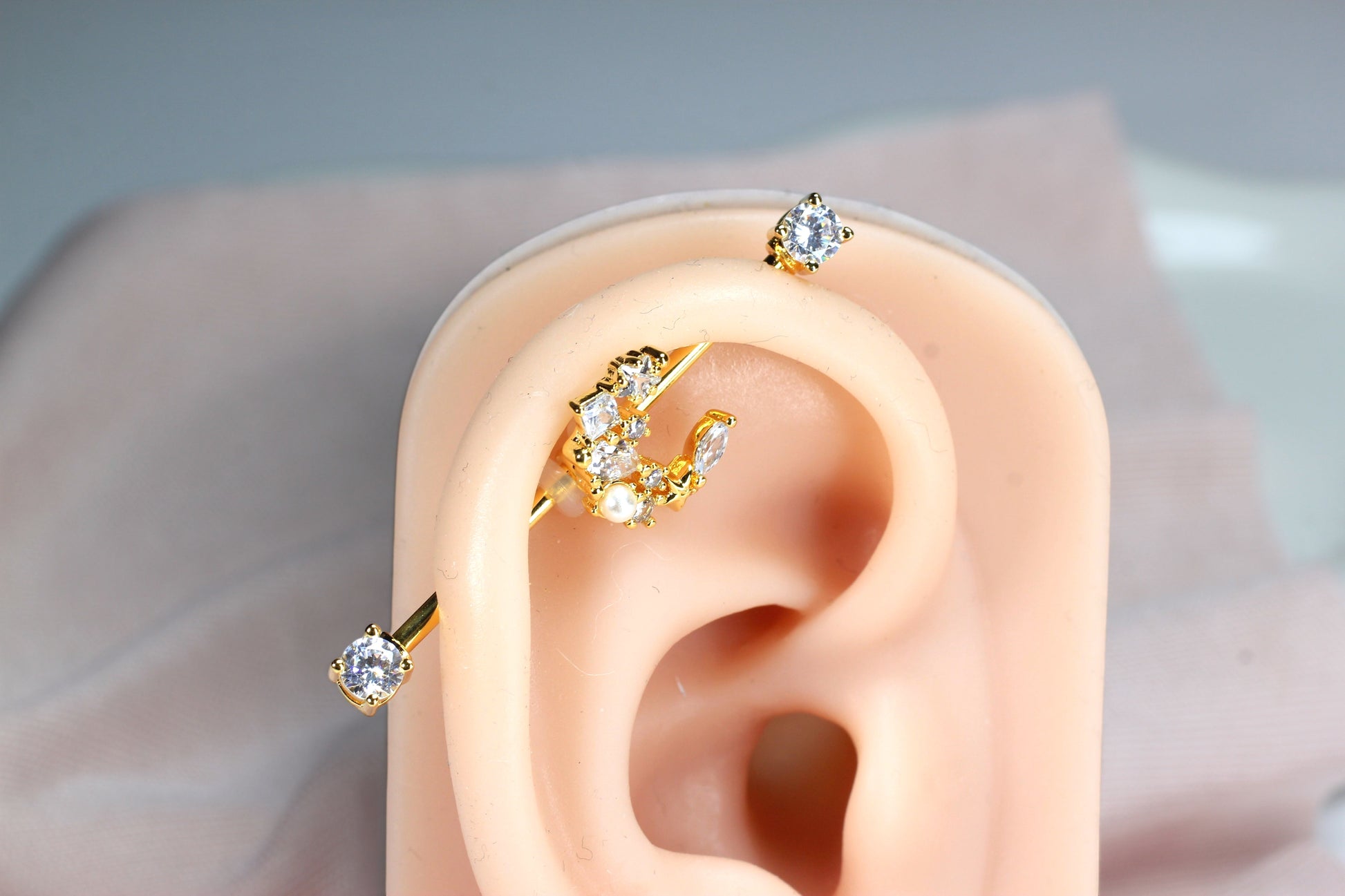 MKBodyJewelry gold industrial barbell with a crescent moon charm adorned with cubic zirconia and pearls.