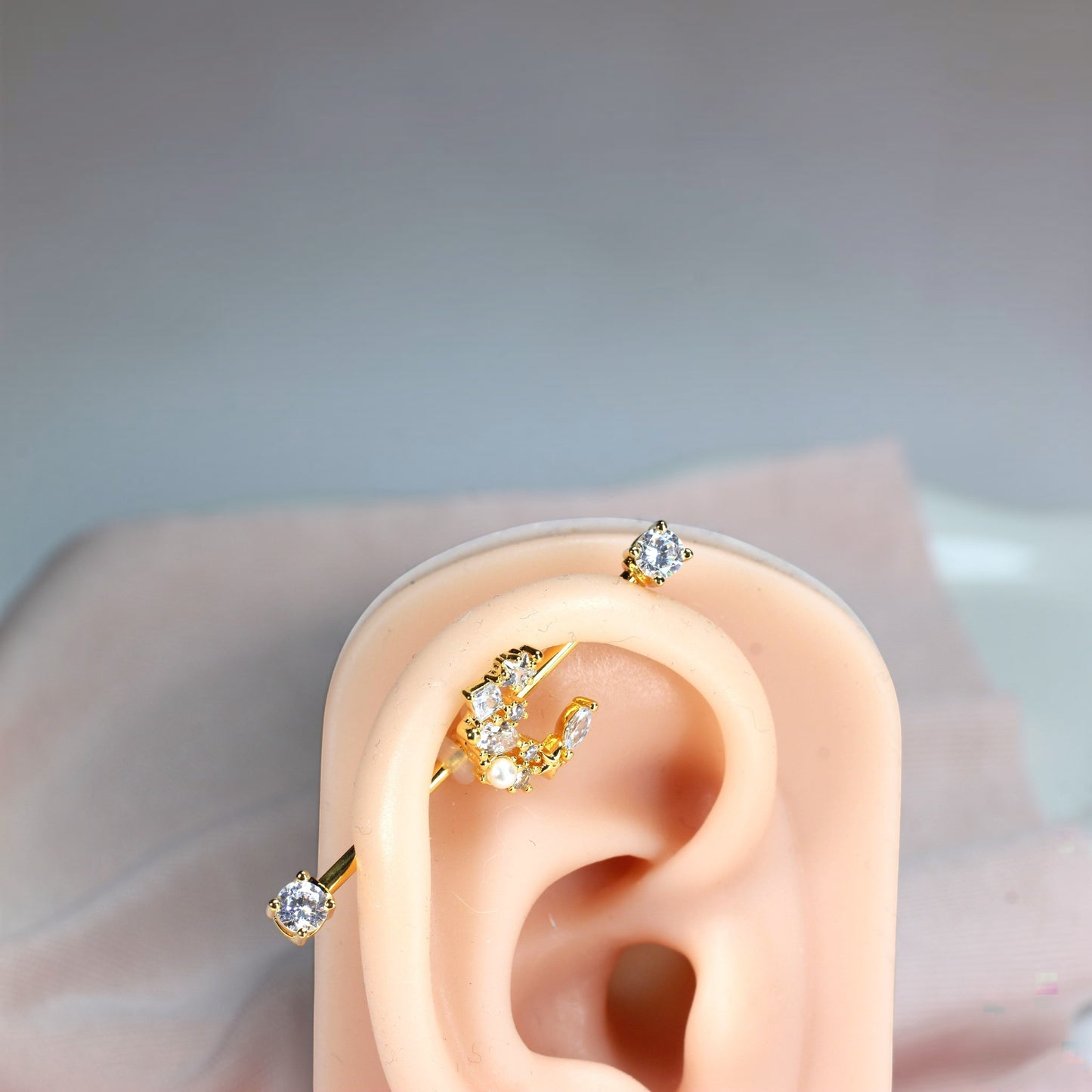 MKBodyJewelry gold industrial barbell with a crescent moon charm adorned with cubic zirconia and pearls.
