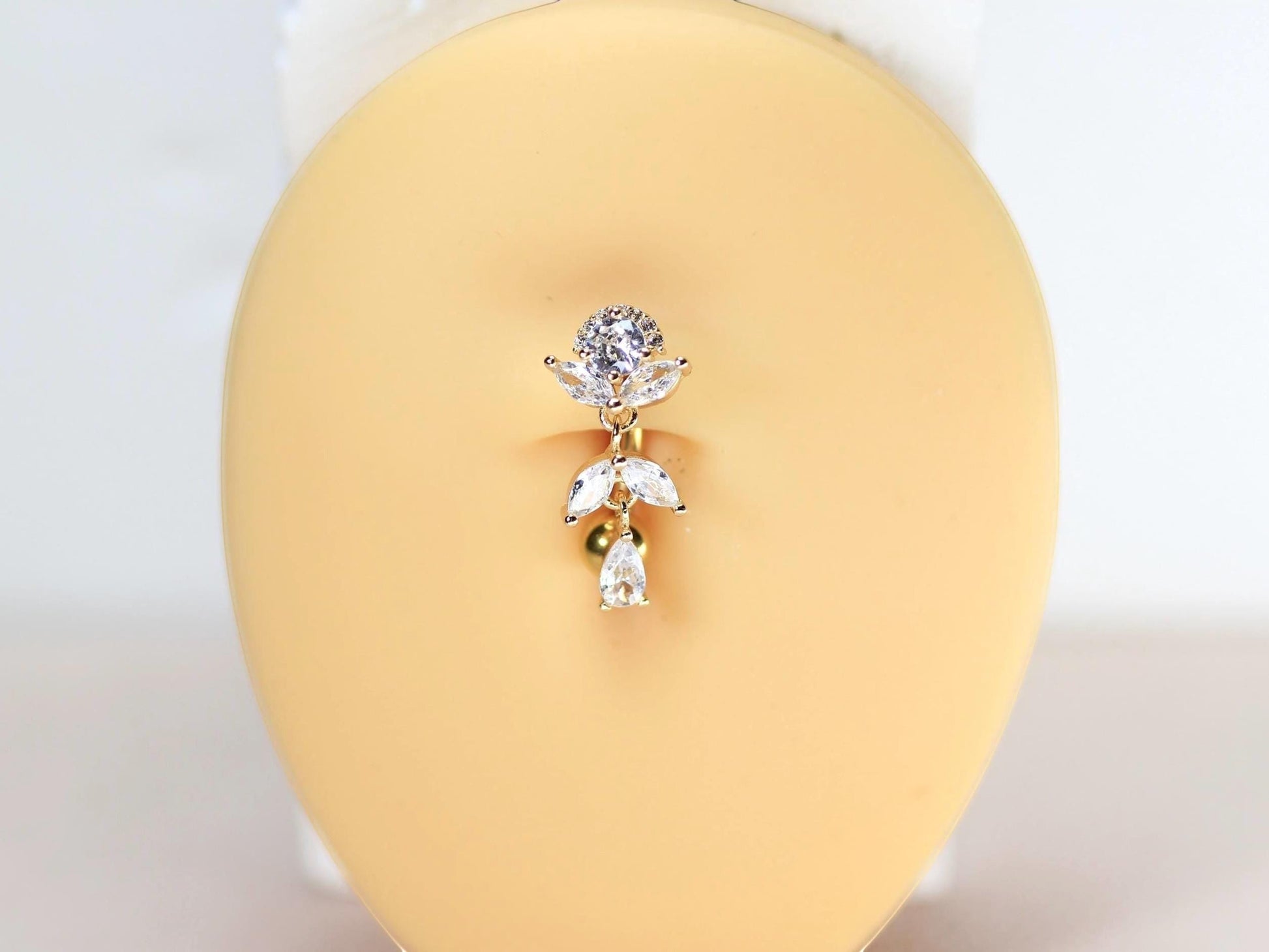 MKBodyJewelry gold inverted floral titanium belly button ring with CZ stones and dangling charms.