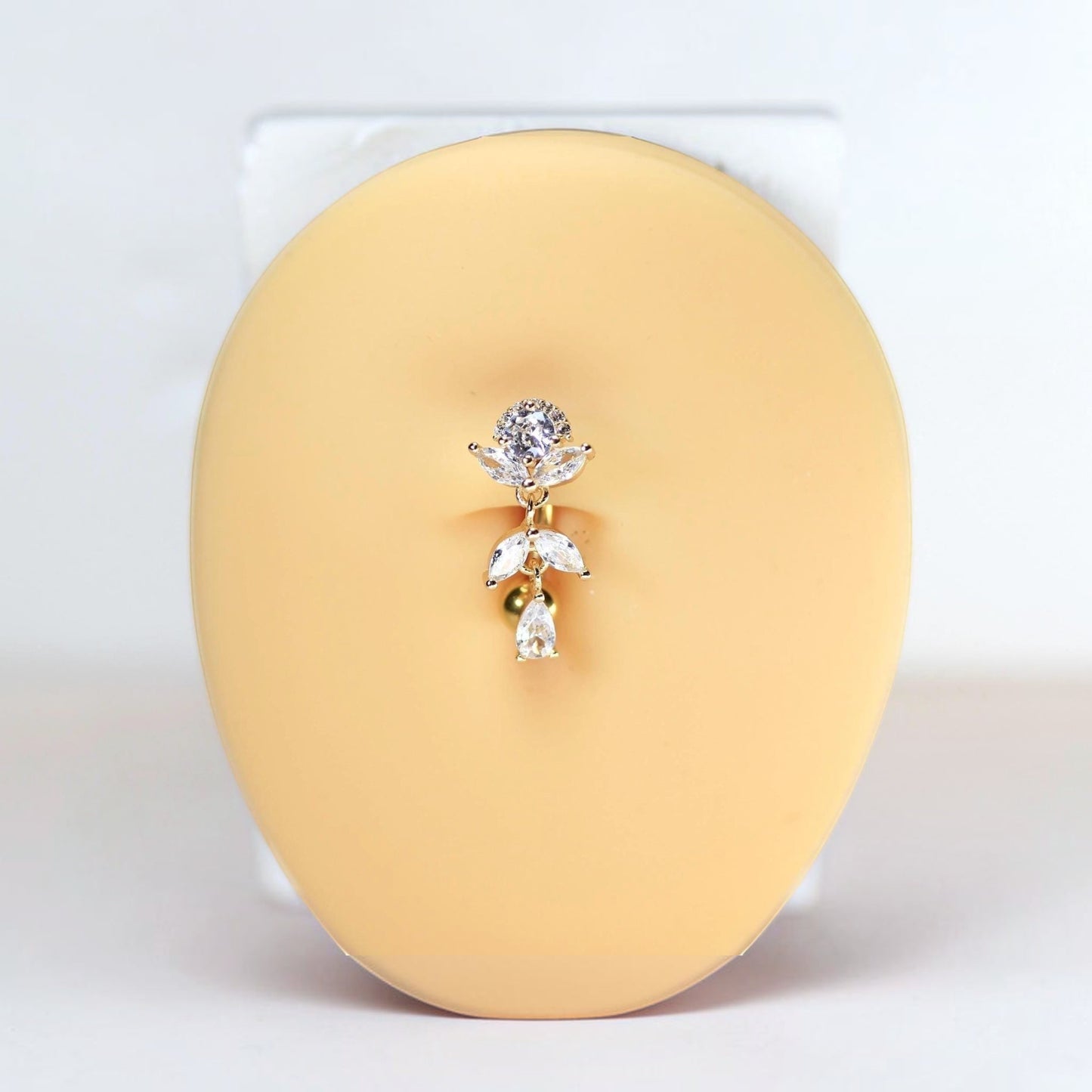 MKBodyJewelry gold inverted floral titanium belly button ring with CZ stones and dangling charms.
