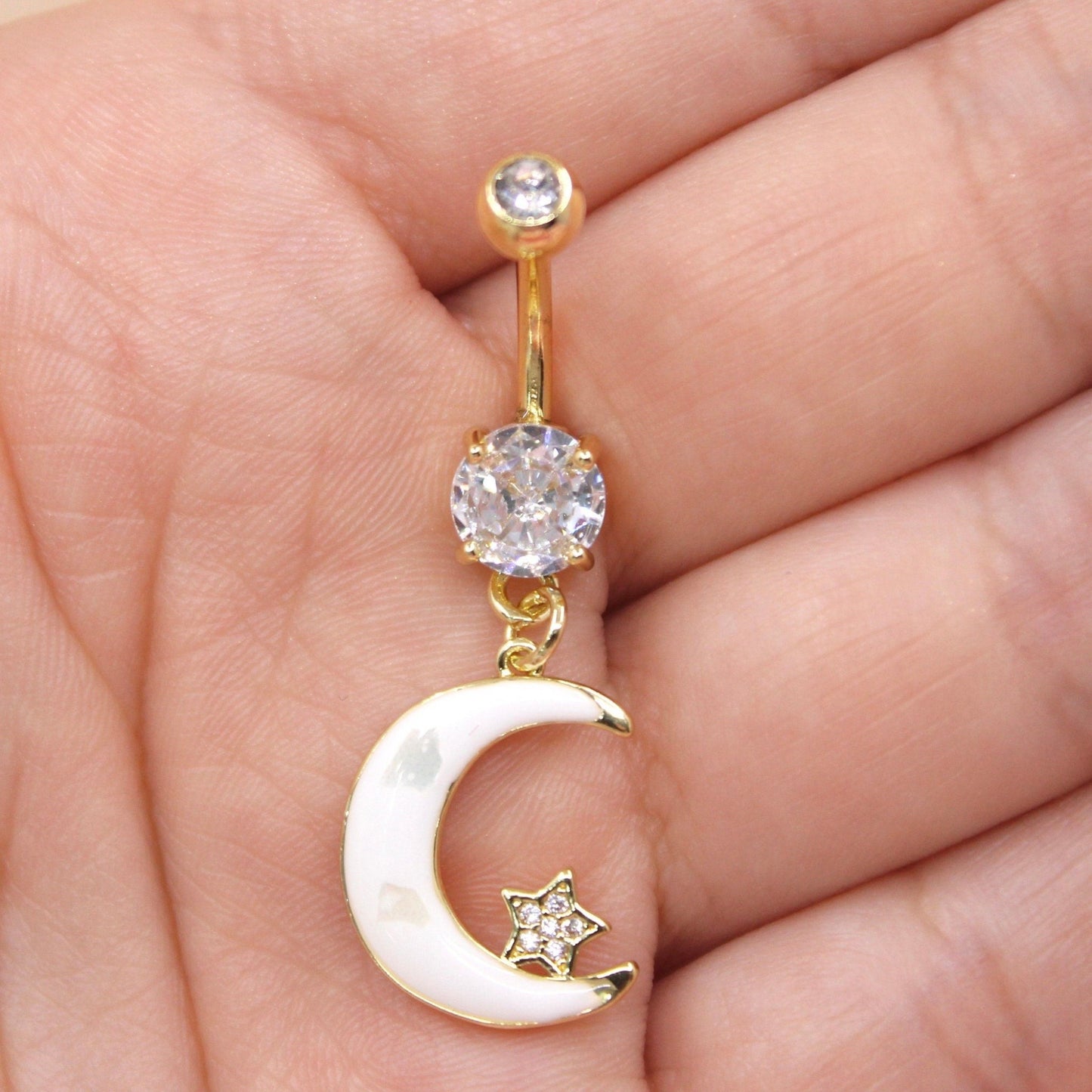 MKBodyJewelry gold stainless steel belly button ring with a white crescent moon charm and clear crystal accents.