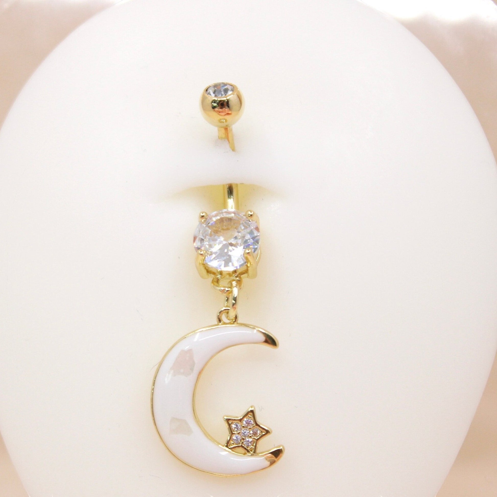 MKBodyJewelry gold-tone stainless steel belly button ring with a white enamel moon charm and sparkling crystal accents