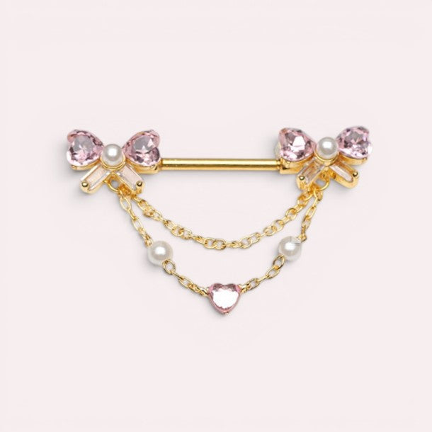 MKBodyJewelry gold 14g nipple barbell with pink bow charms, pearl accents, and a dangling heart chain.