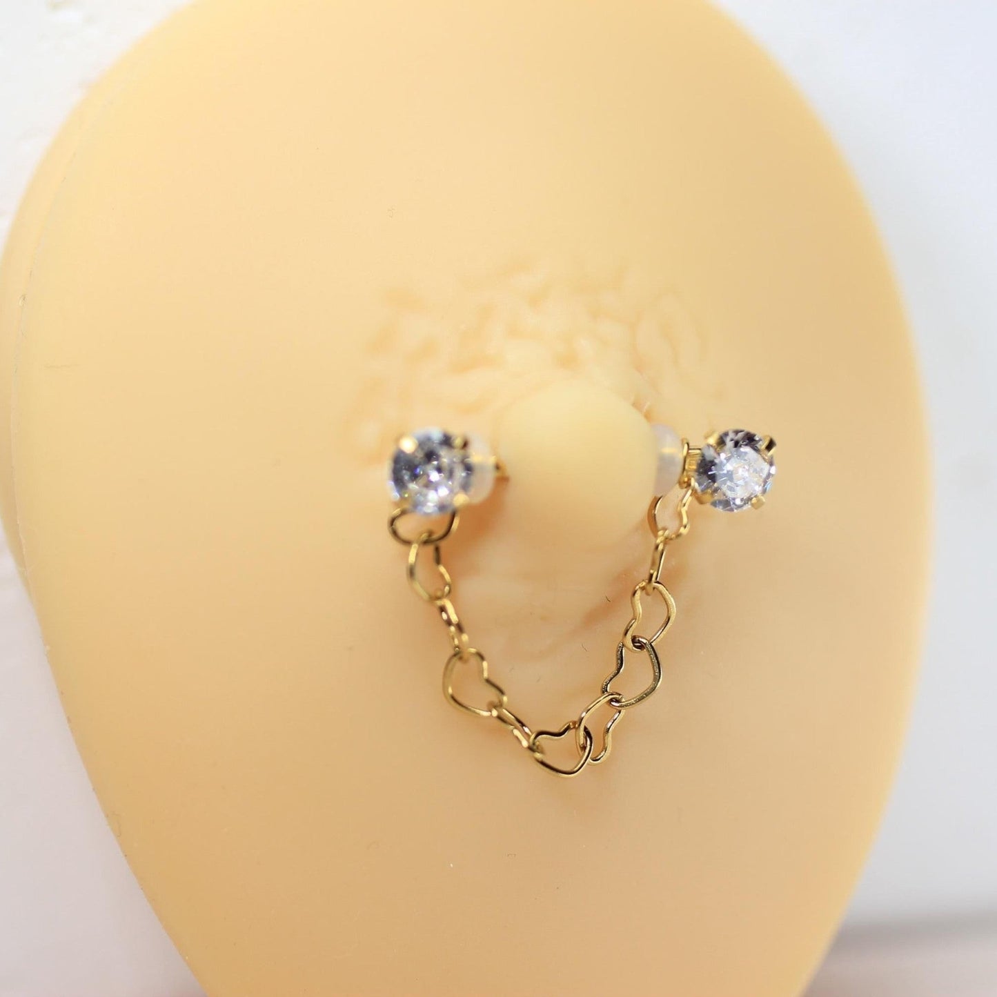 MKBodyJewelry gold 14g surgical steel nipple barbell with dangling heart chain and CZ prong ends.